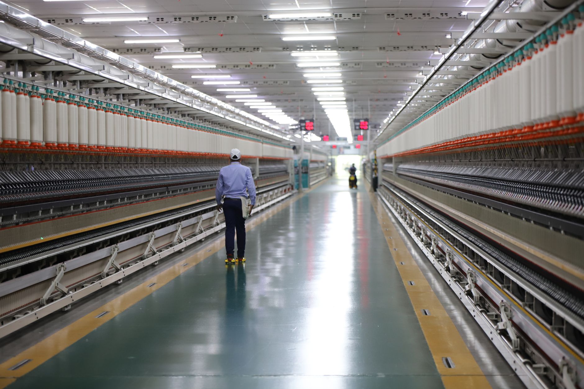 Factory worker walking a repetitive route along an industrial aisle, illustrating the wasted travel that a transfer cell can remove.