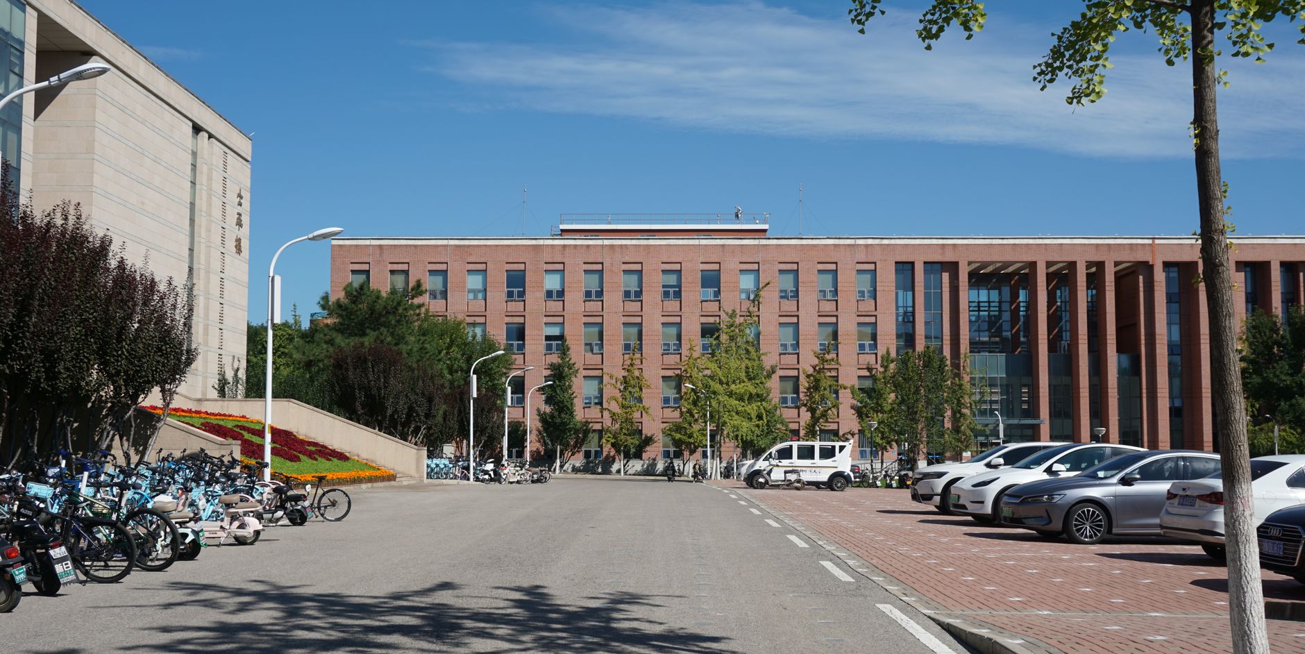 A large campus parking area beside academic buildings, showing the long exterior edges and approaches that need periodic patrol coverage.