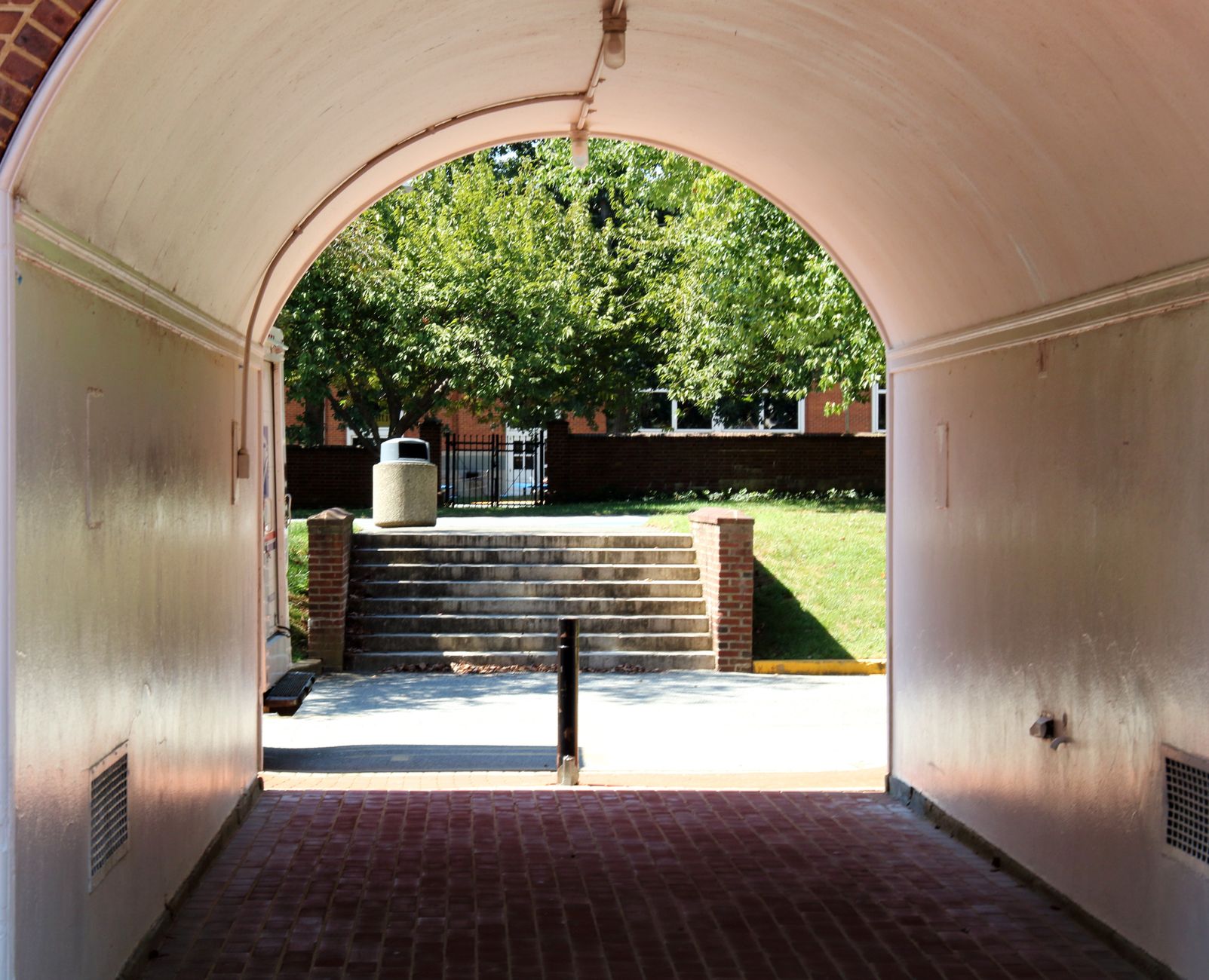 A winding paved walkway on a corporate campus features both flat stretches and stairs, illustrating the varied terrain security robots must navigate.