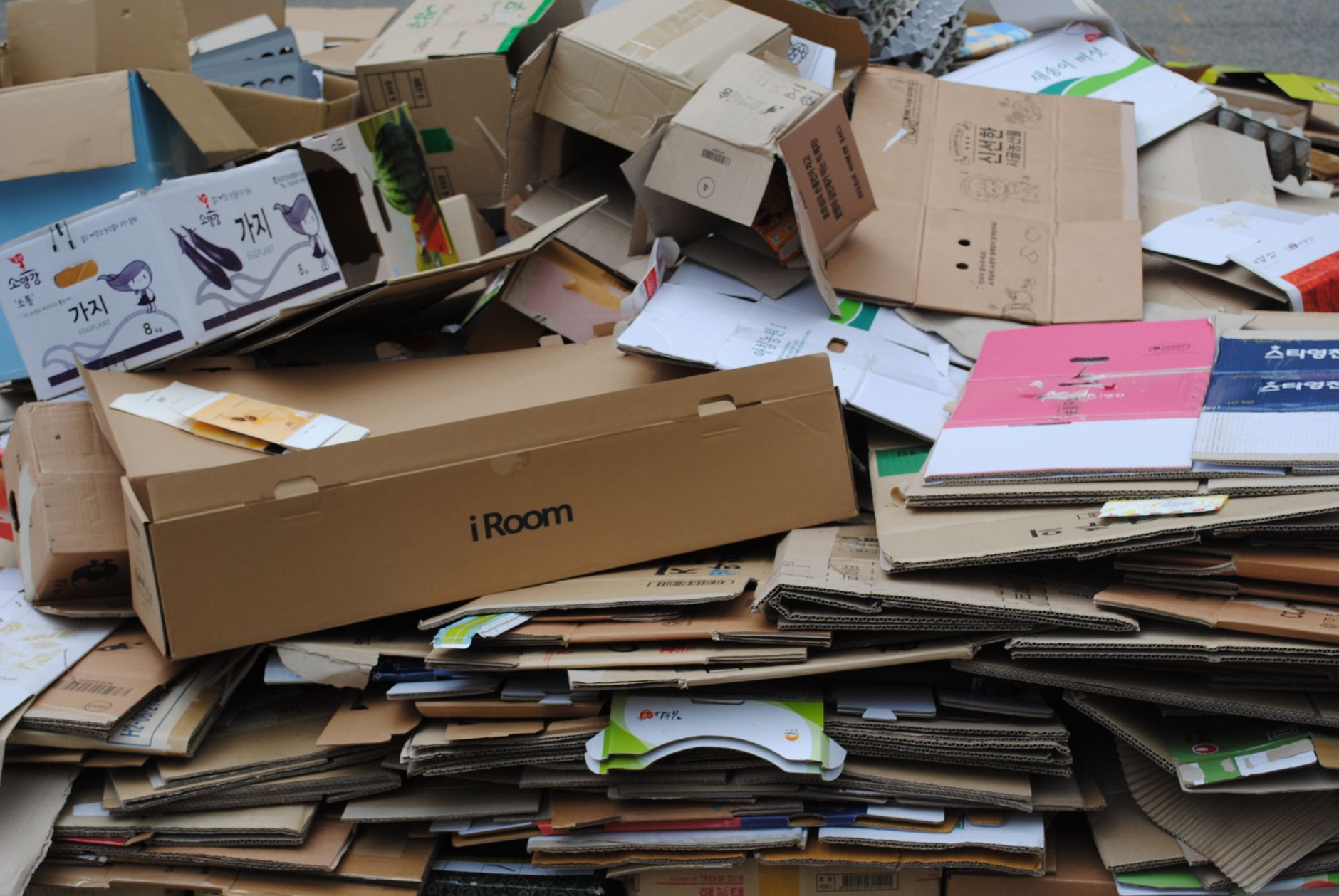 Loose cardboard and plastic wrap scattered on a warehouse concrete floor near pallet staging.