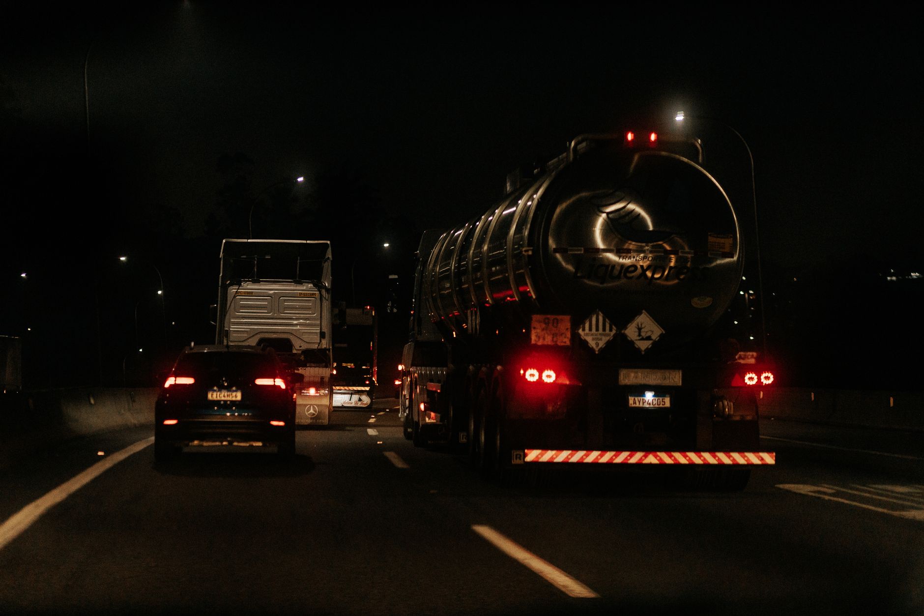 A truck on a highway at night, evoking the travel time between distant sites when a technician cannot reach two failures the same evening.