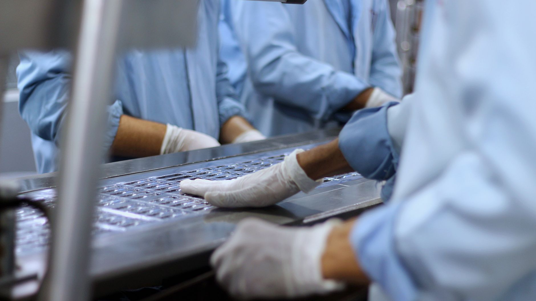 Workers assemble small medical devices at close-set stations in a space-conscious production facility.