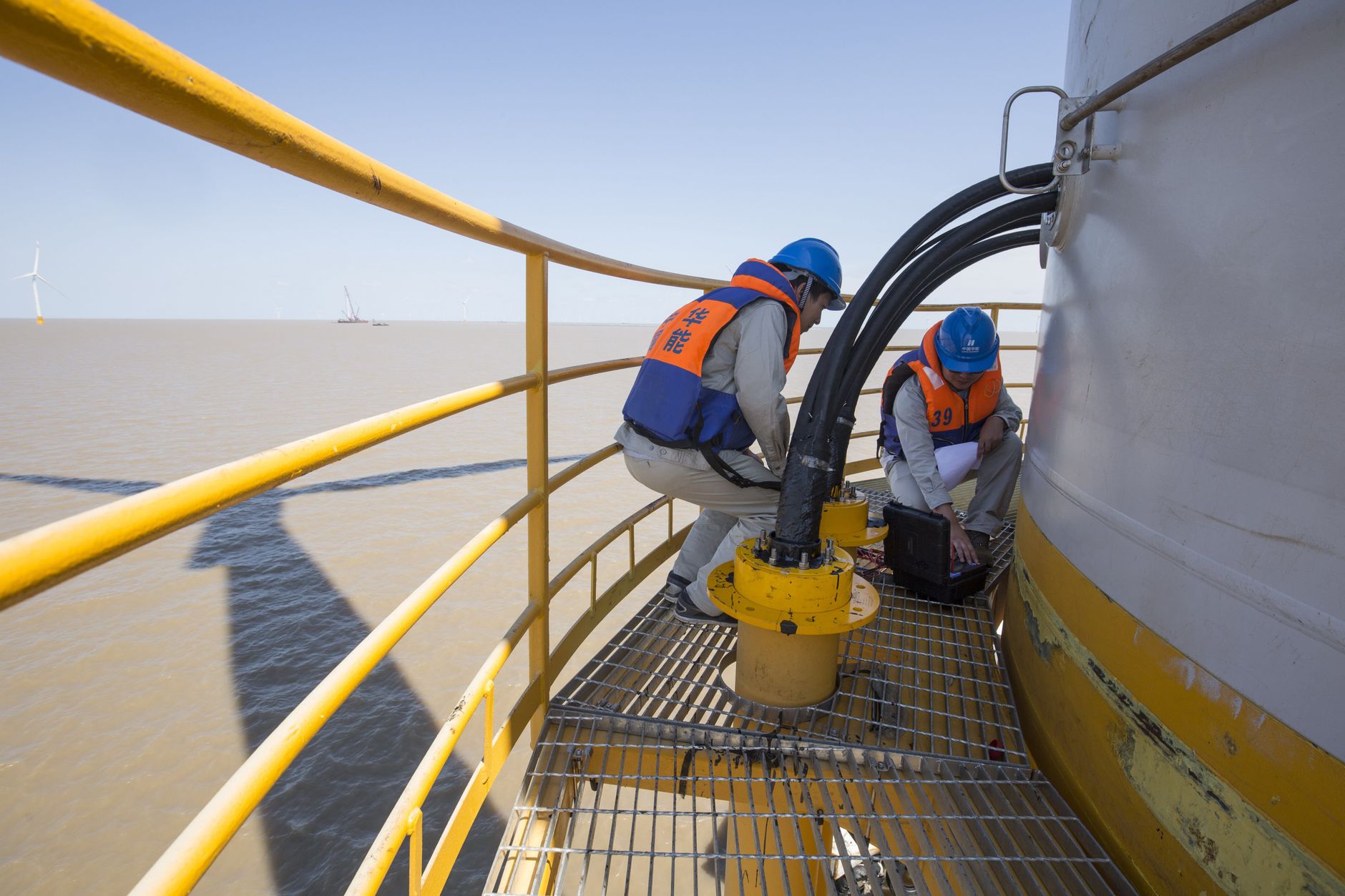 Wind-energy technicians survey a turbine site, reflecting the people and field support required throughout a commercial maintenance program.