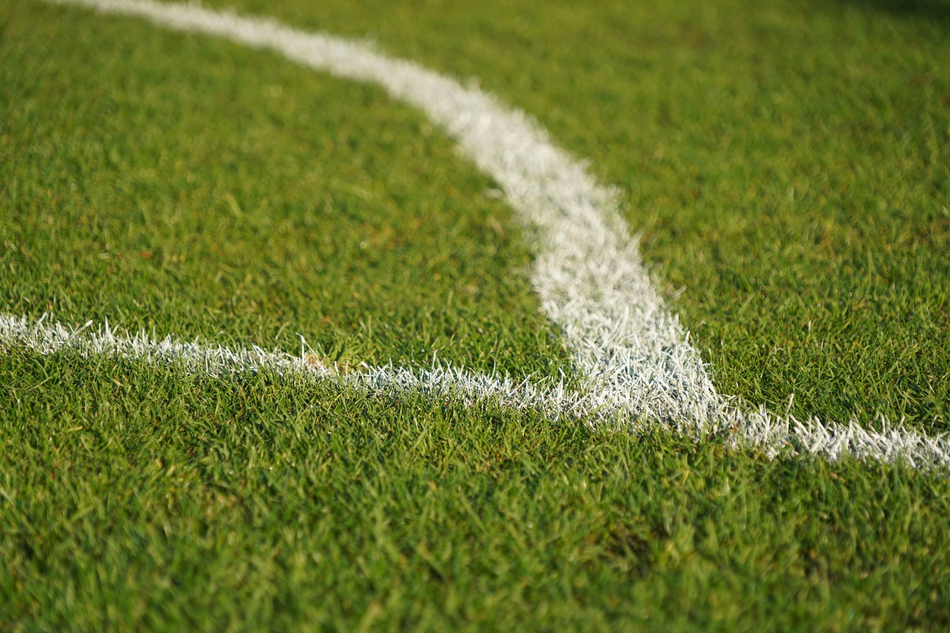 A groundskeeper working along a sports field suggests the setup and upkeep work that still surrounds line marking at a busy complex.