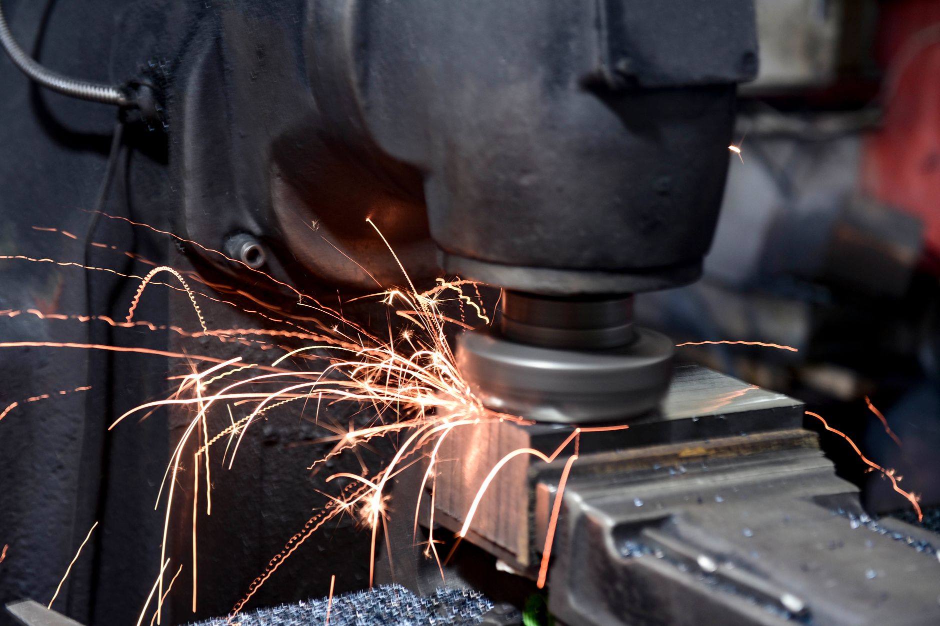 A worker on the floor of a compact metal-parts shop surrounded by production equipment.