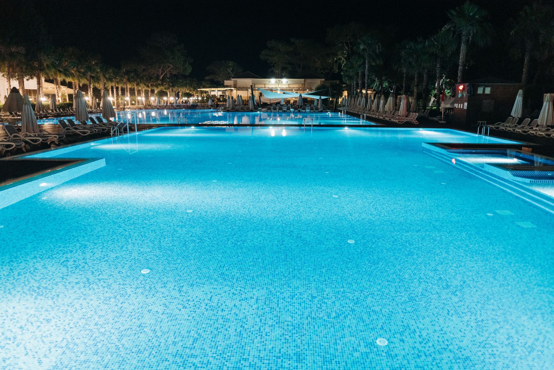 Pool-cleaning tools arranged beside the water for an after-hours hotel maintenance routine.
