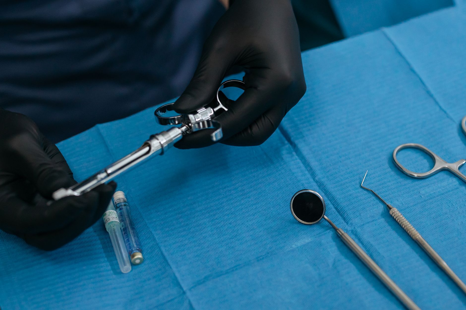 A gloved pharmacy professional carefully preparing a sterile syringe for hospital use.