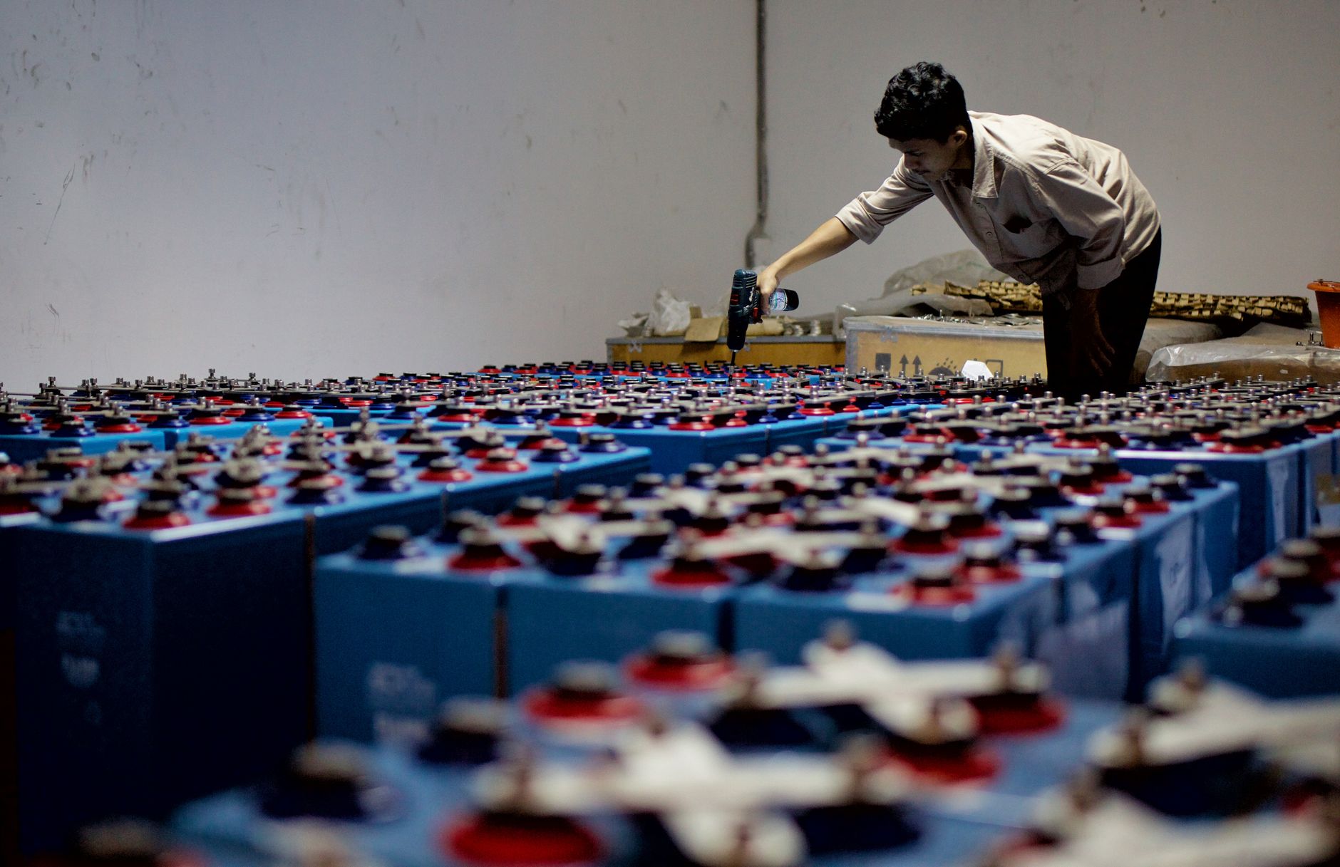 Workers carry out production tasks inside a large lithium-ion battery manufacturing facility.