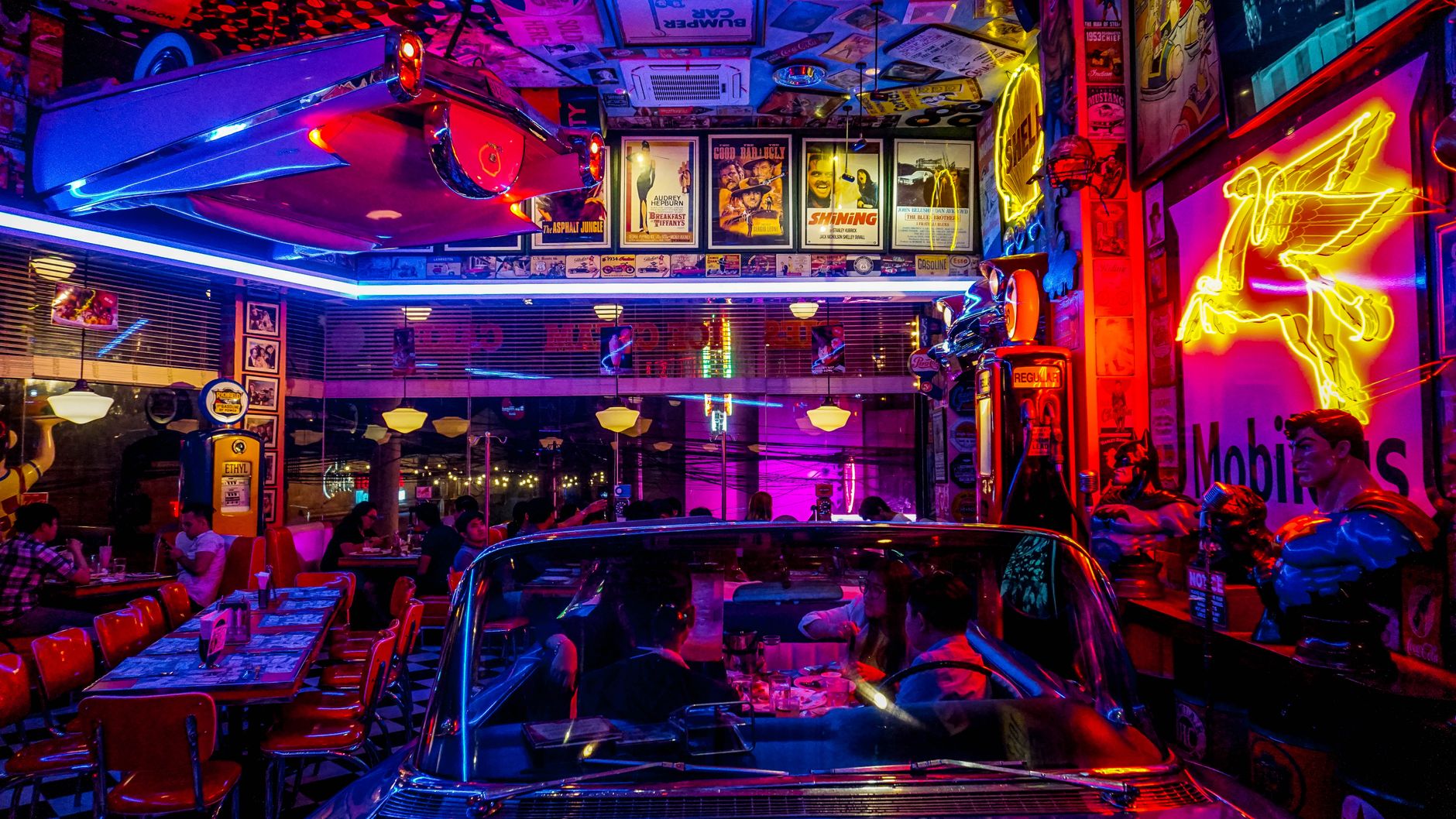A crowded restaurant dining room with many tables set for service under warm lighting.
