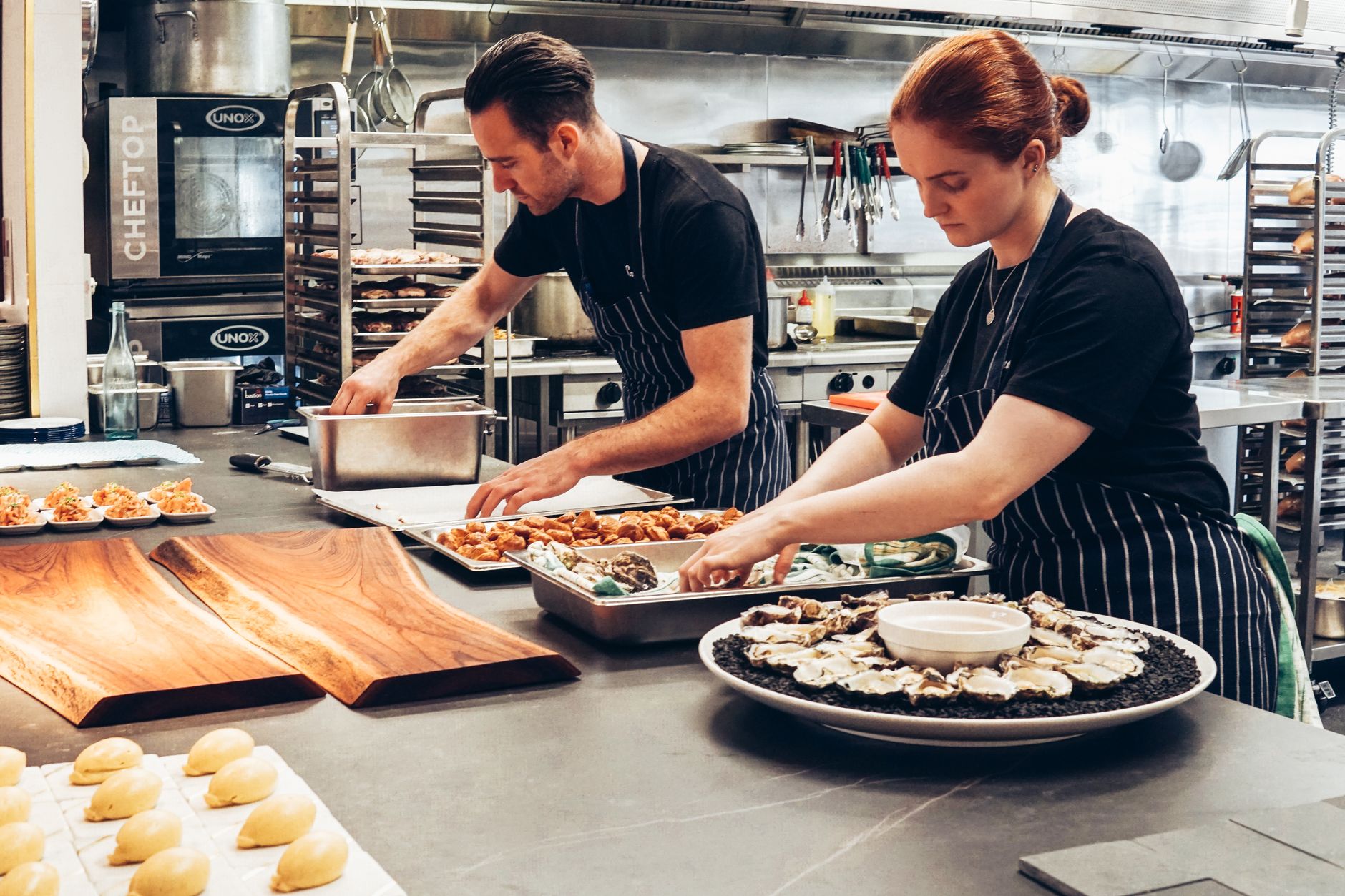 Kitchen staff plate dishes during a high-volume restaurant service period.