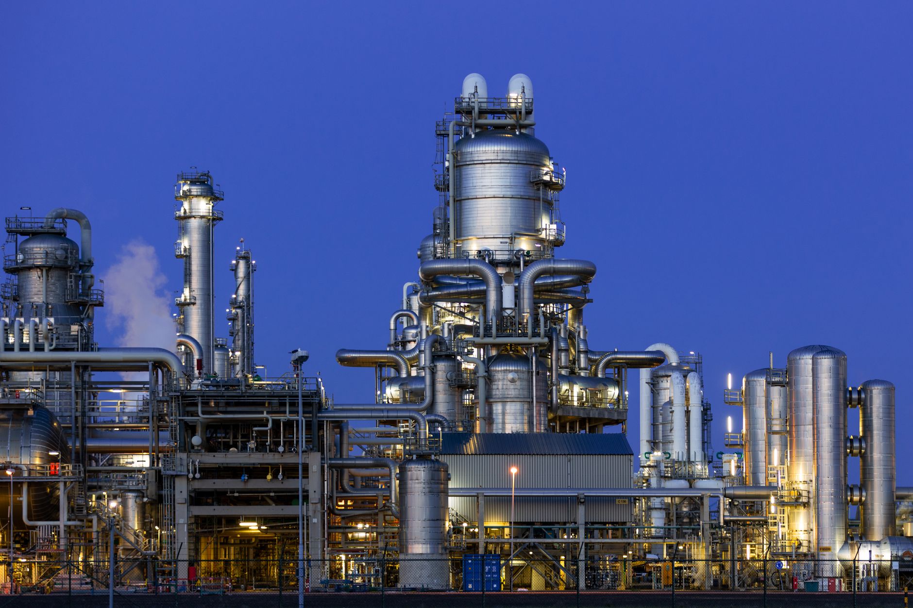 Dense refinery piping and tank infrastructure show the obstacles involved in inspecting a filled storage vessel.