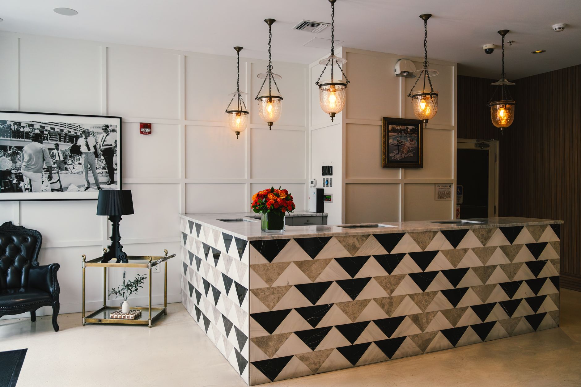A receptionist remains at the front desk of a welcoming boutique hotel lobby.