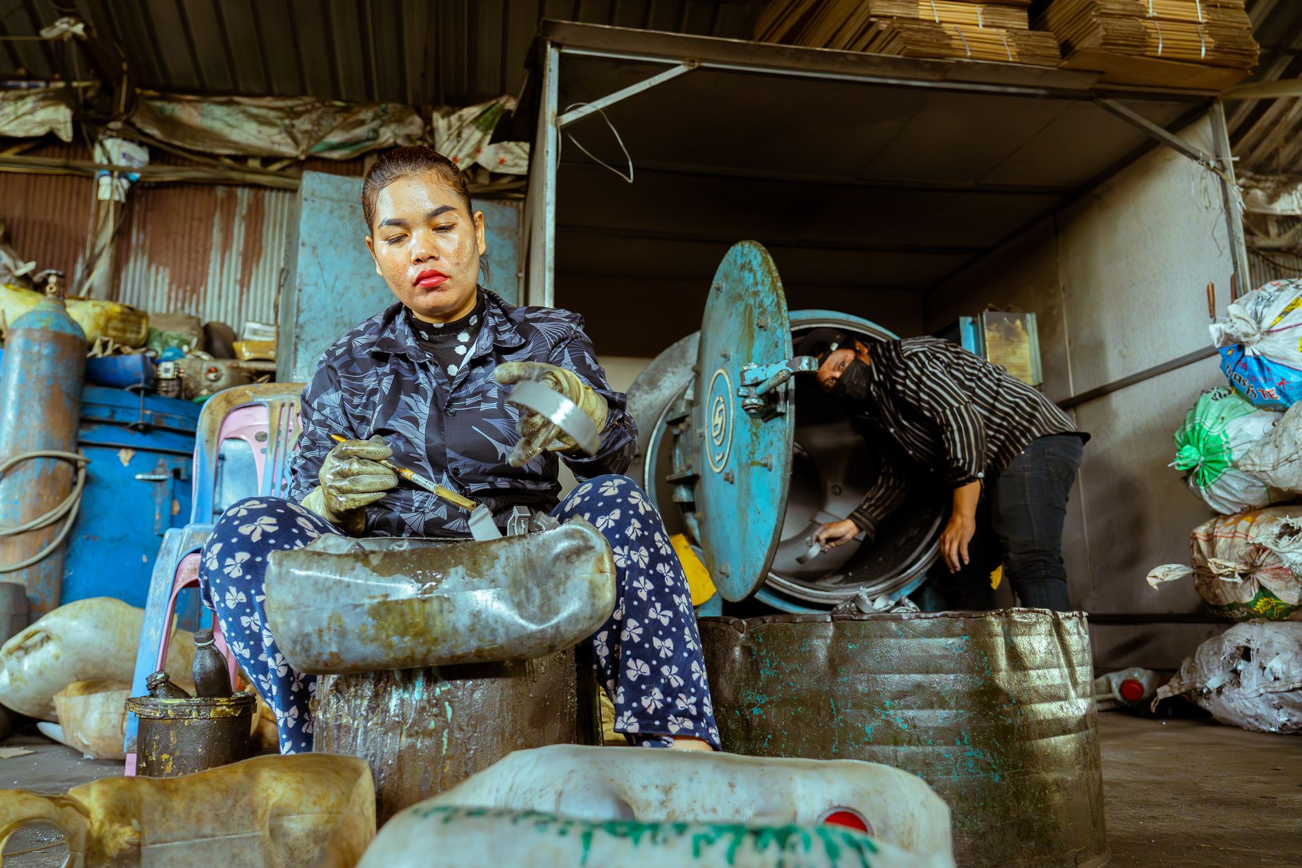 A worker carries plastic bins through a factory corridor between floors.
