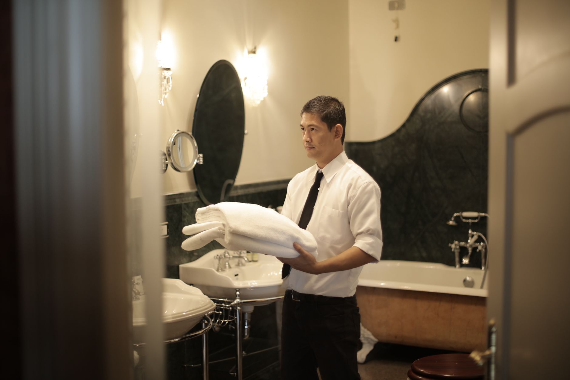 Housekeeping cart staged in a hotel hallway while staff focus on room turns instead of vacuuming.