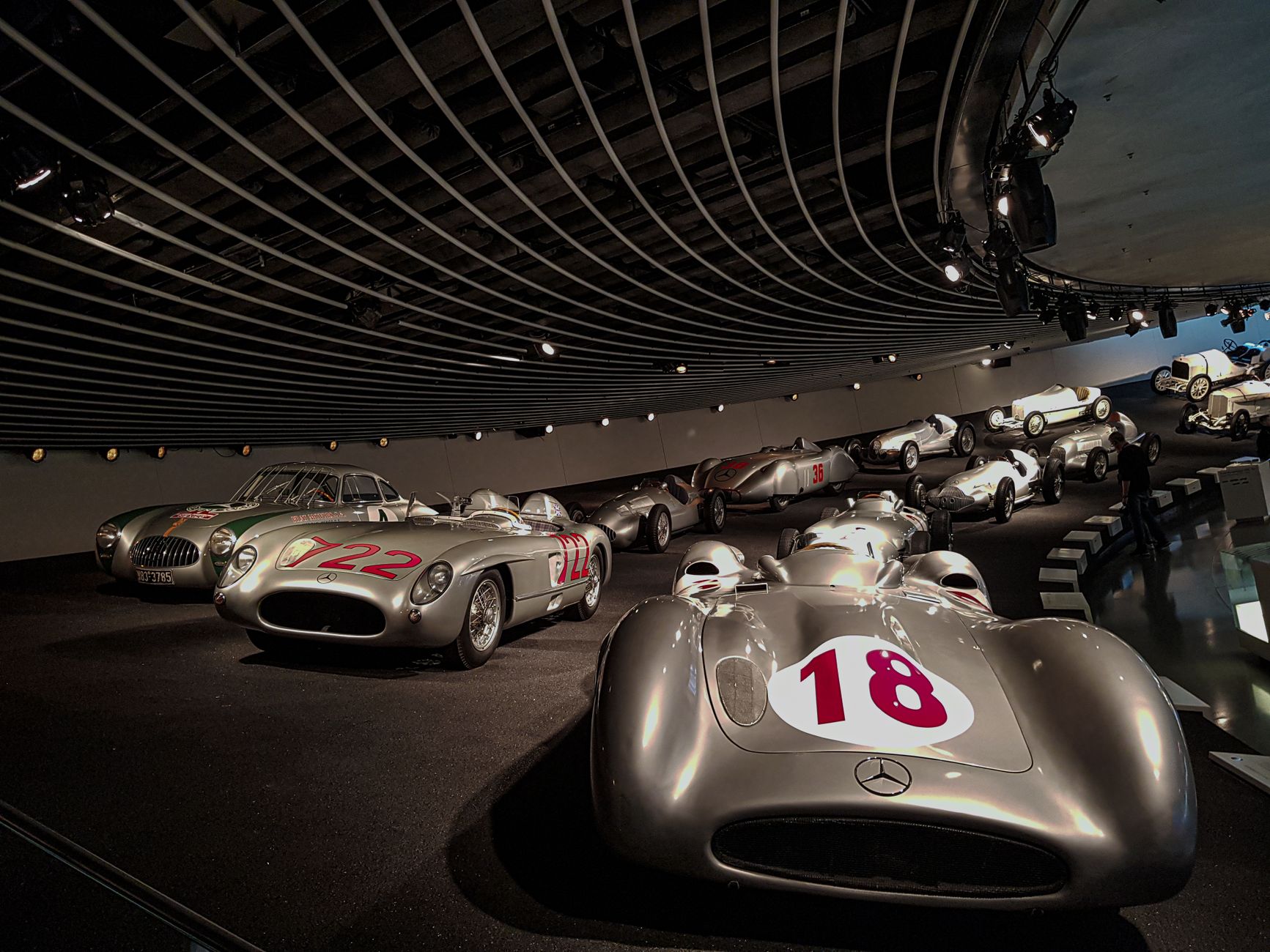 Polished floors surround classic cars displayed inside a spacious museum gallery.