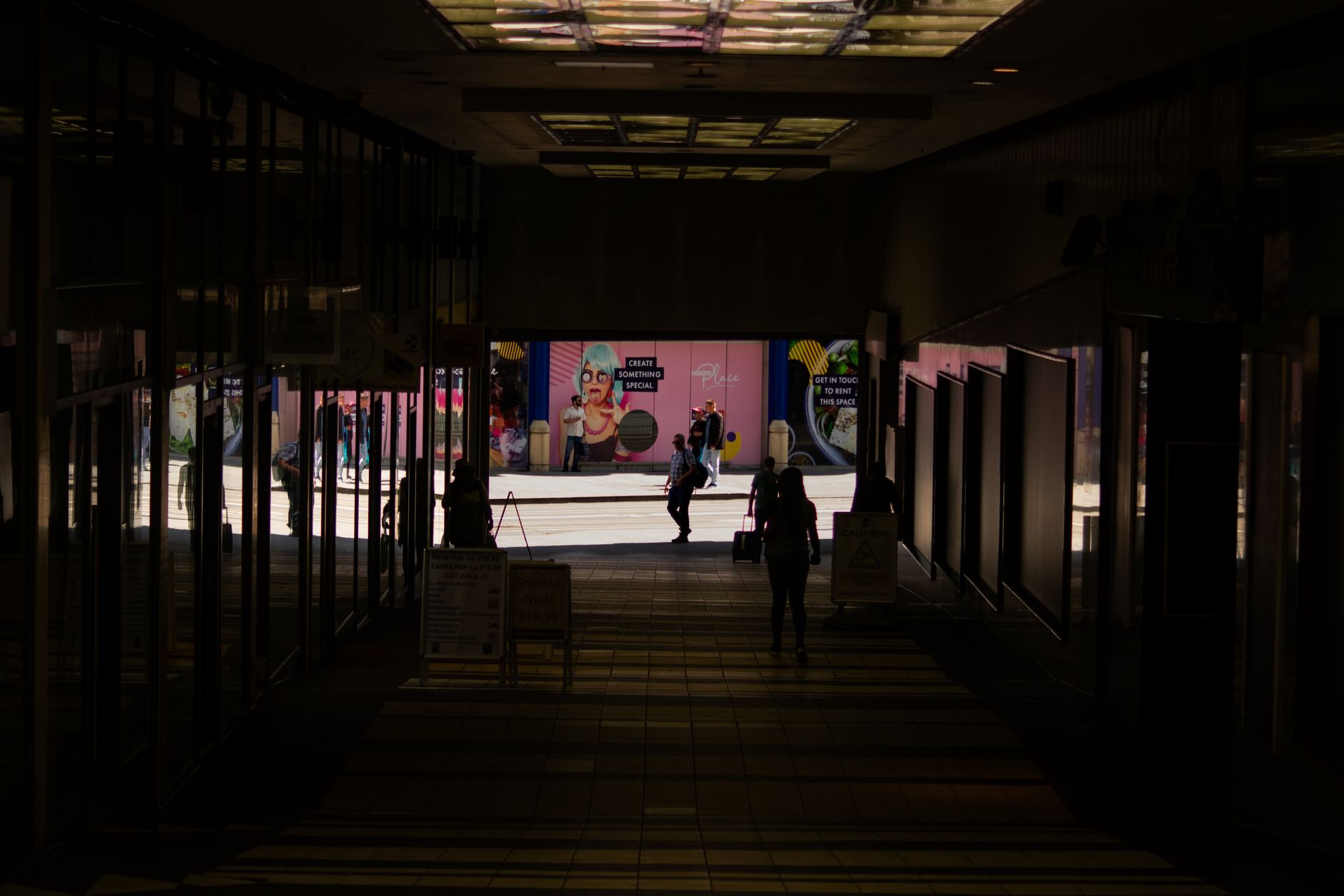 A wide shopping mall concourse where contract cleaners run autonomous scrubbers after hours.