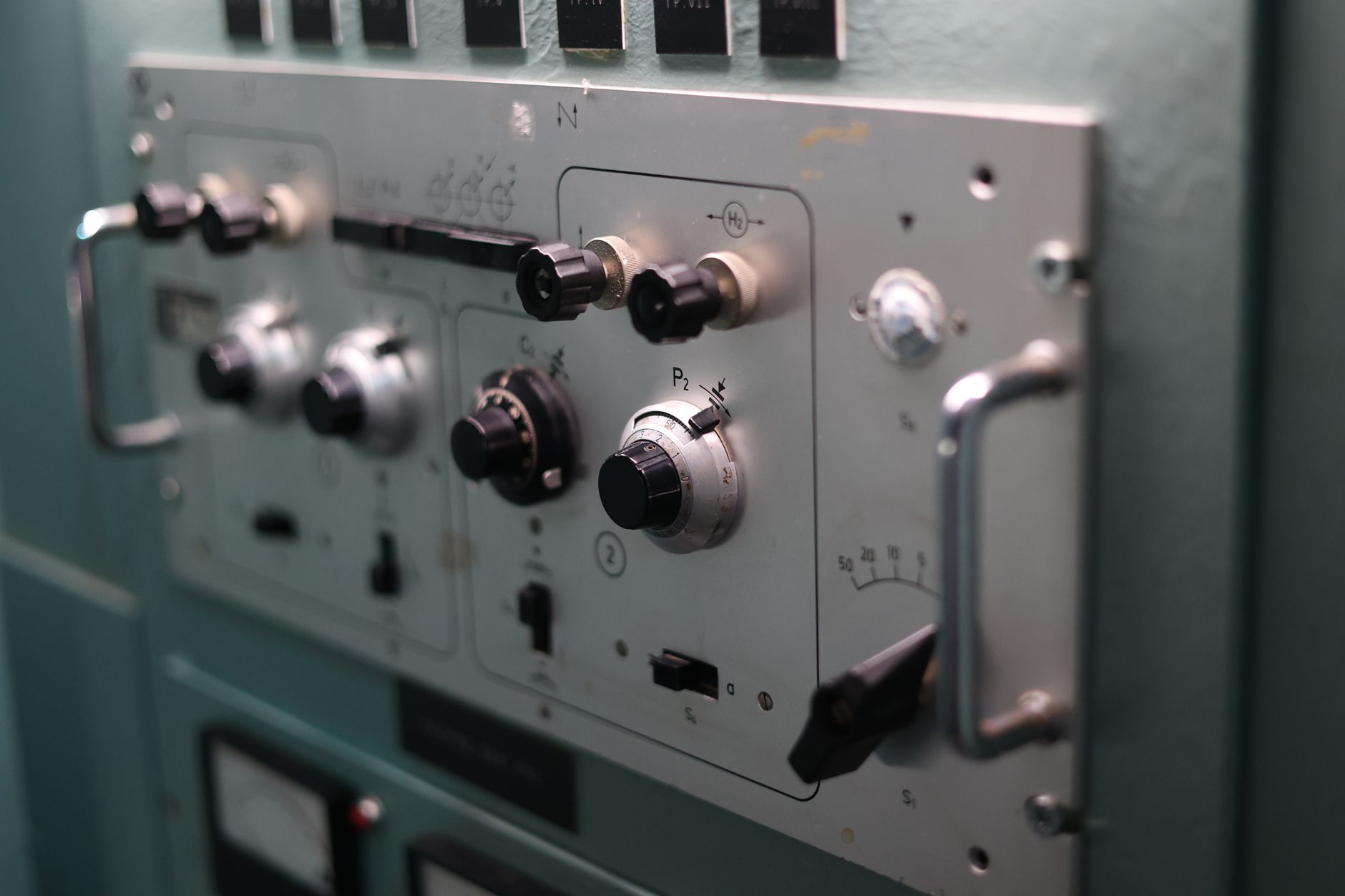 An operator at an industrial control panel, staying at the machine while material moves elsewhere.
