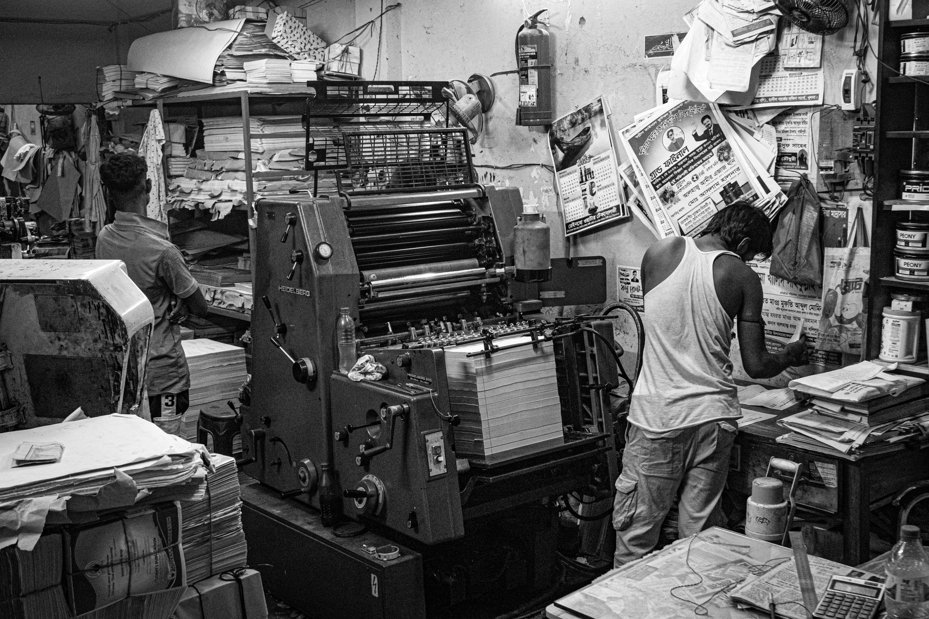 Wide view of a commercial printing floor with large presses and worktables, setting the scene for a case study about plate-change labor in a small print shop.
