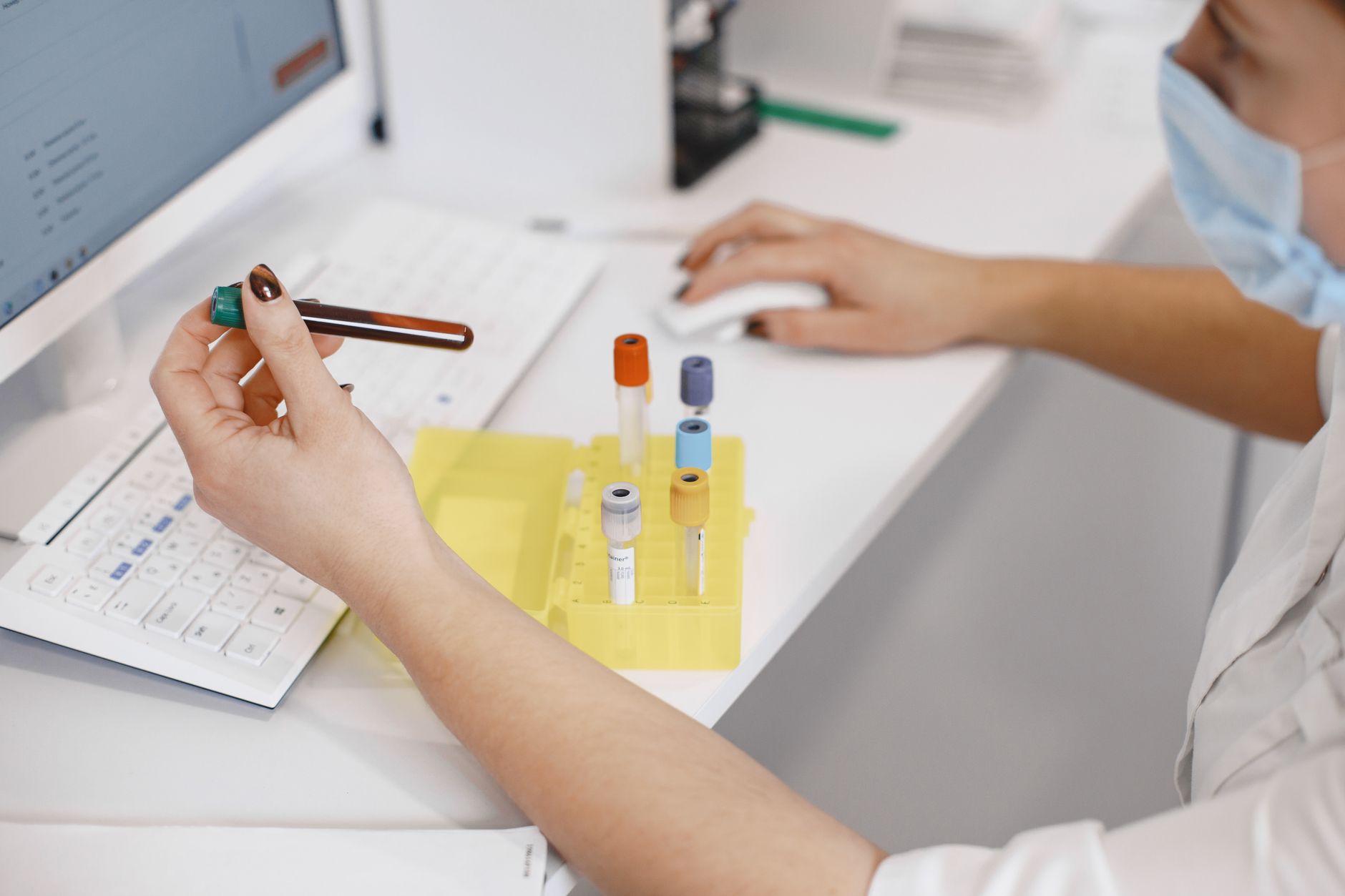 A hospital laboratory technician handles labeled specimens at a clinical workbench.
