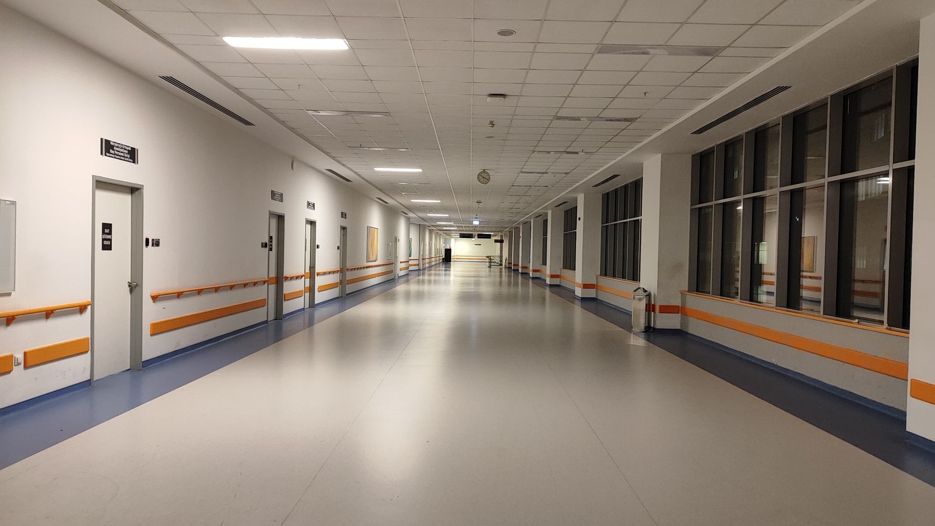 Long hospital corridor with polished tile floors where autonomous scrubbers maintain consistent overnight cleaning coverage.
