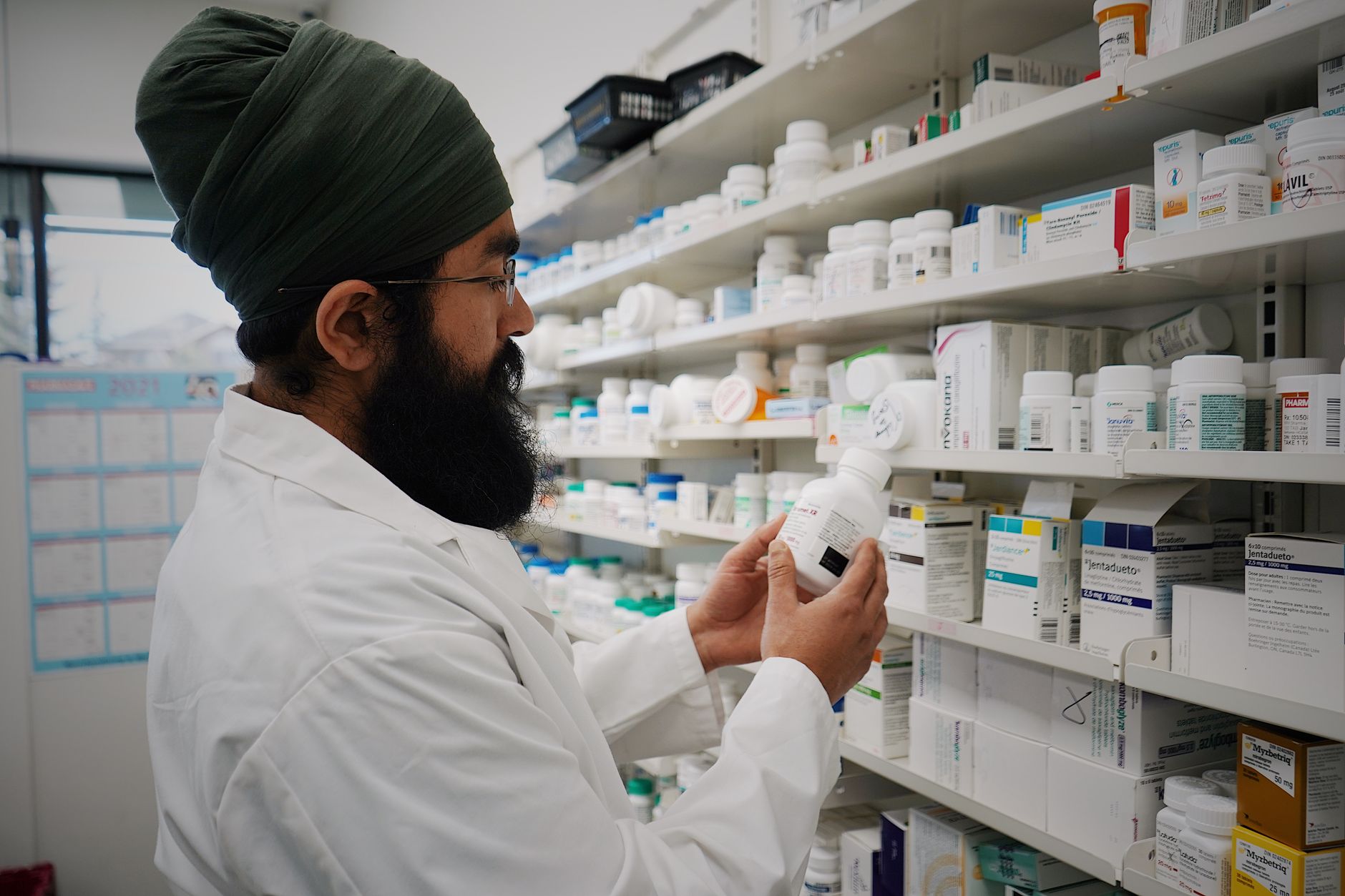 Densely stocked medicine shelves inside a compact community pharmacy dispensary.