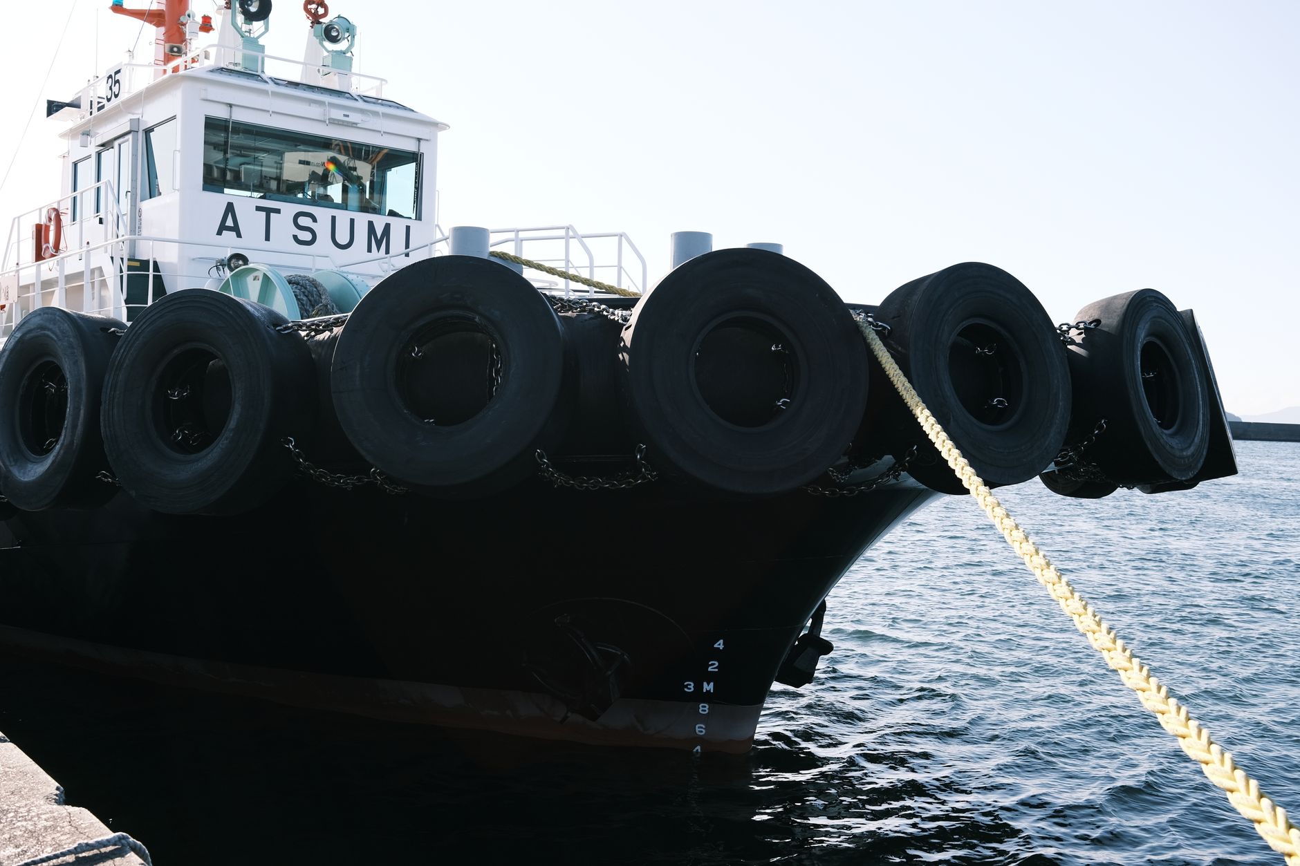 Dock workers handle heavy mooring lines beside a cargo ship at the quay.