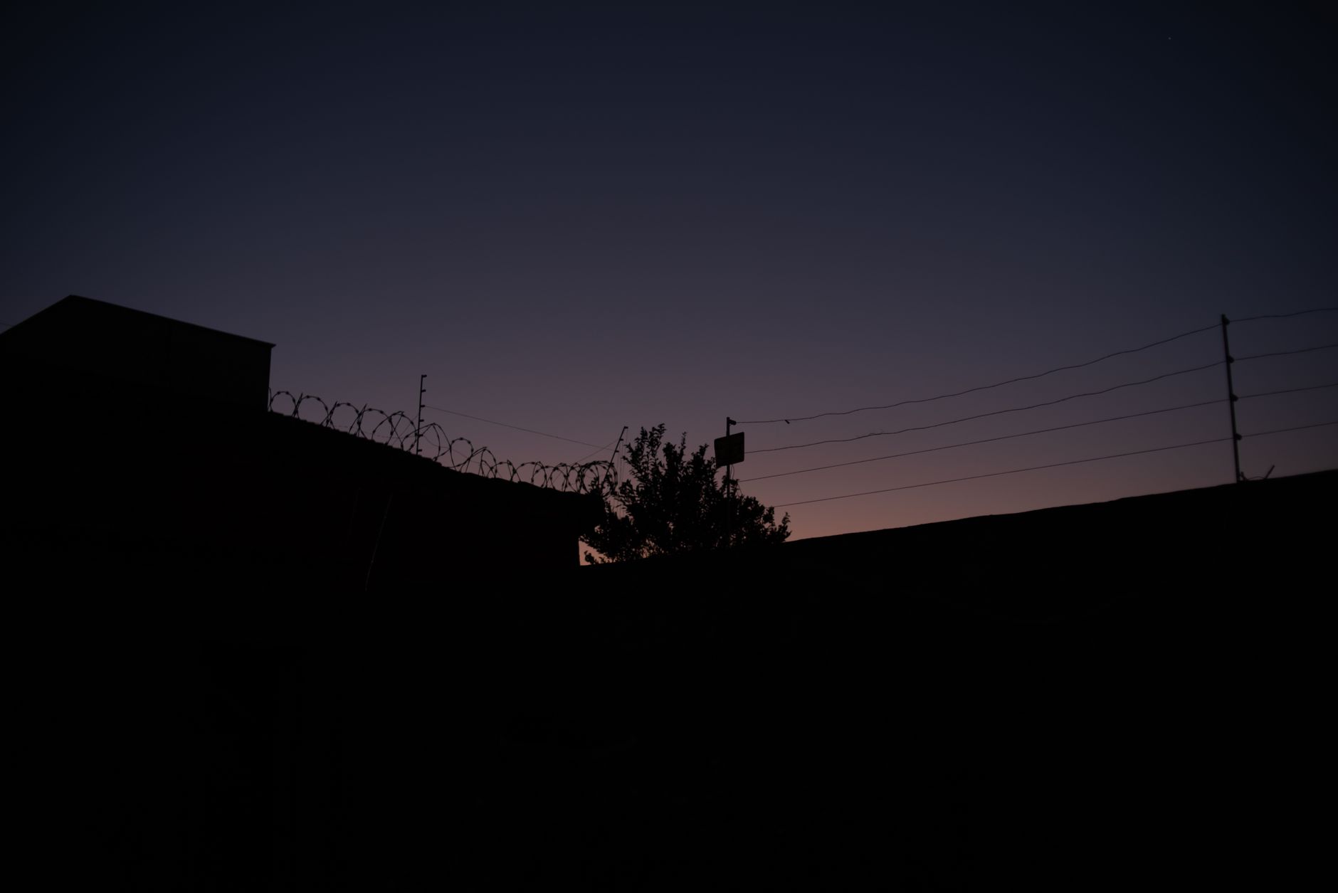 Perimeter fence and yard lighting around an industrial site at night.