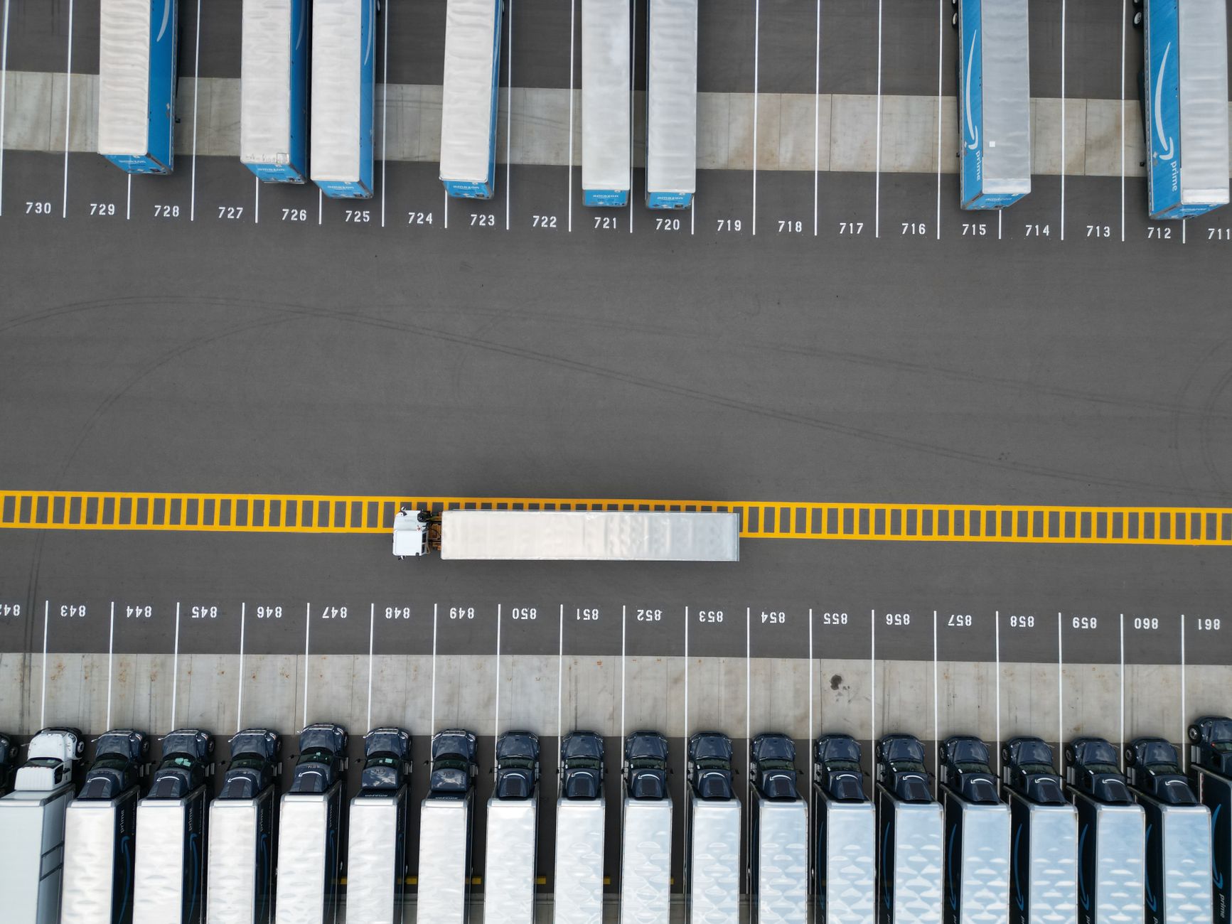 Trucks and trailers at a large distribution center yard at dusk.