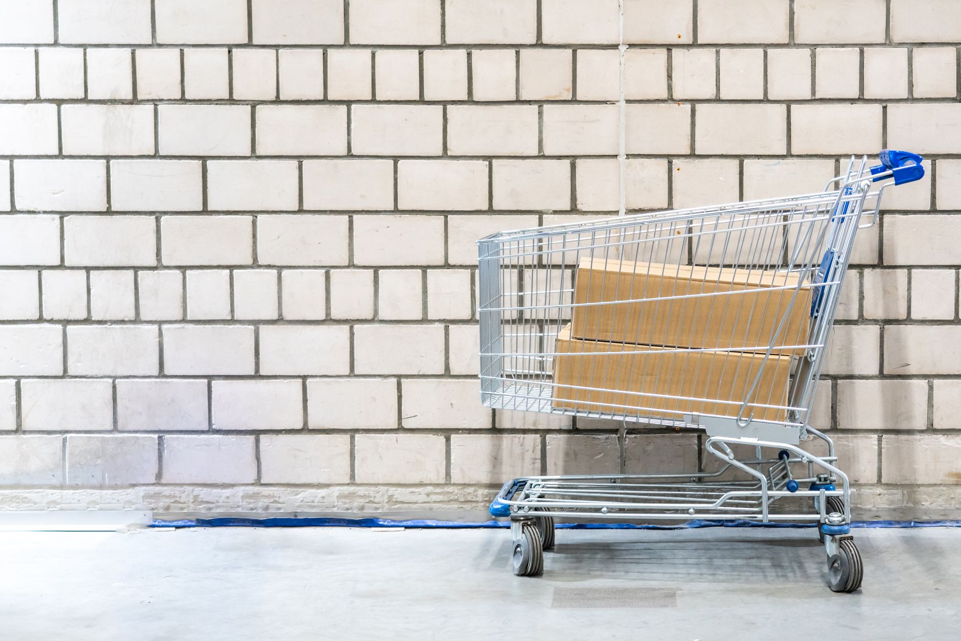 A worker moves cartons on a cart between warehouse racks.
