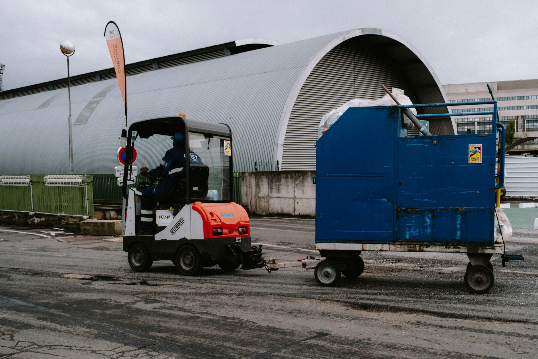 A worker pushes a cart through a busy warehouse corridor.