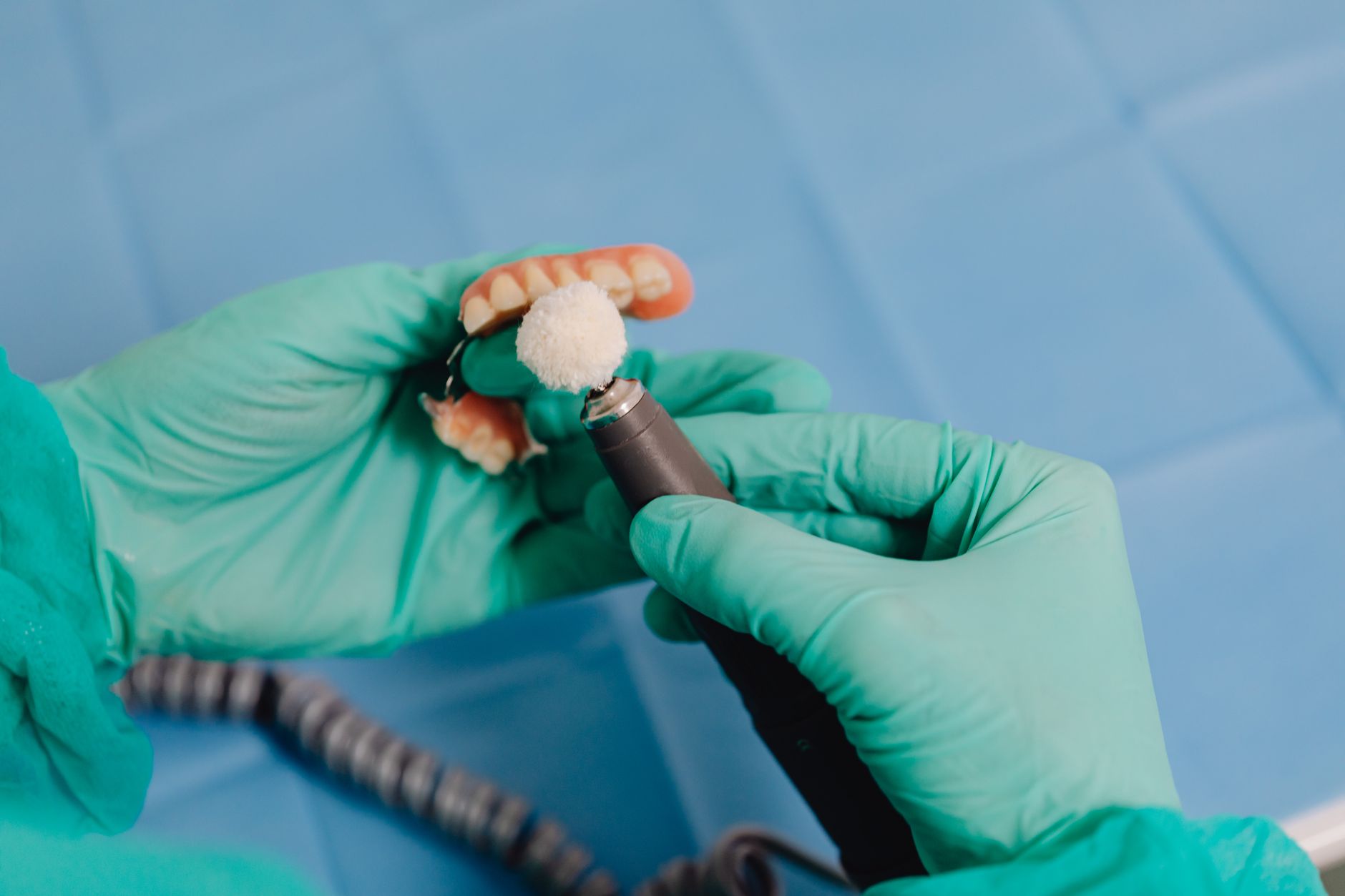 A dental technician working with crown models and lab equipment.