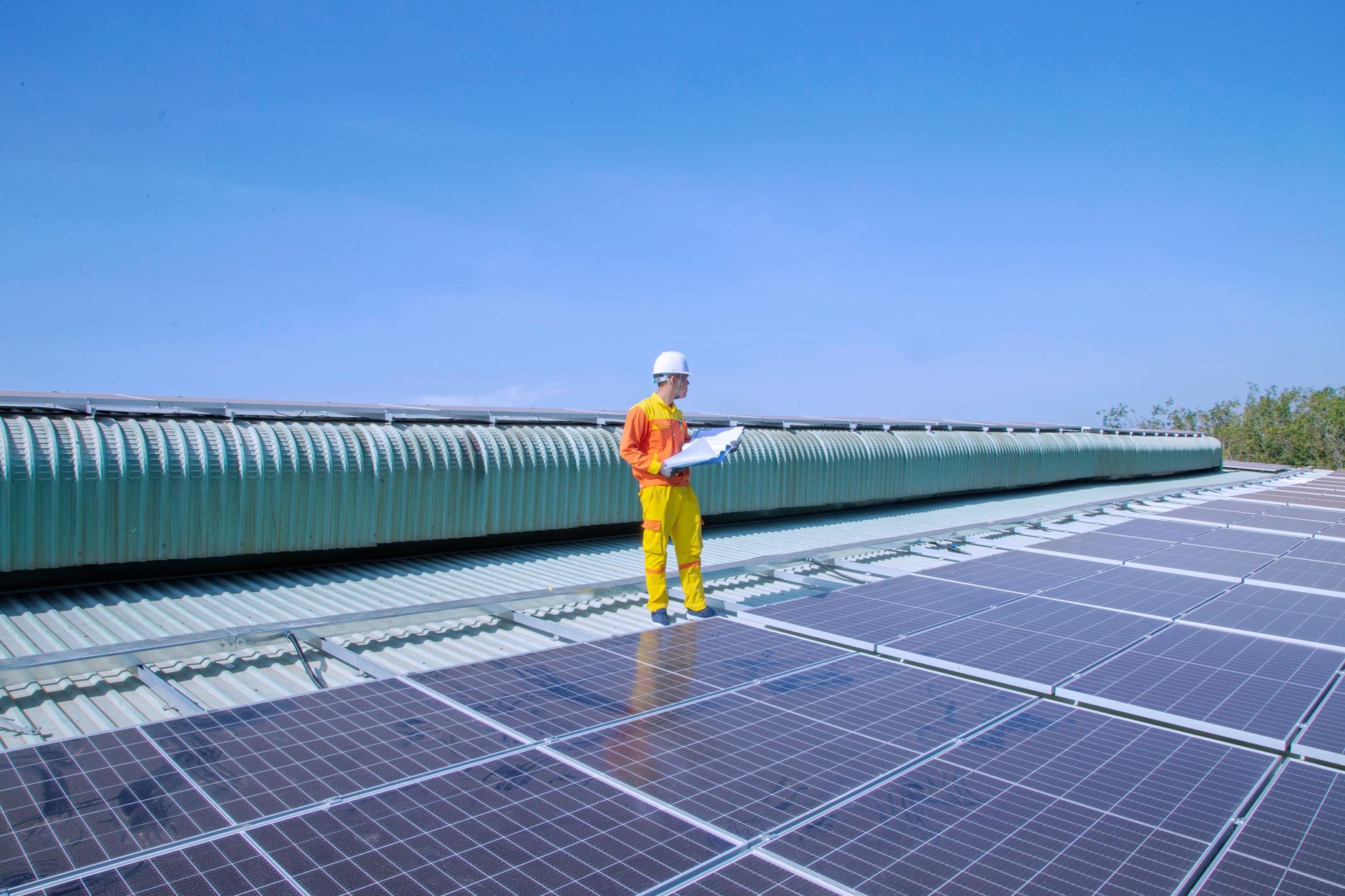 A technician walking along solar panel rows during a site inspection, reflecting the pilot and fit-check work before full deployment.