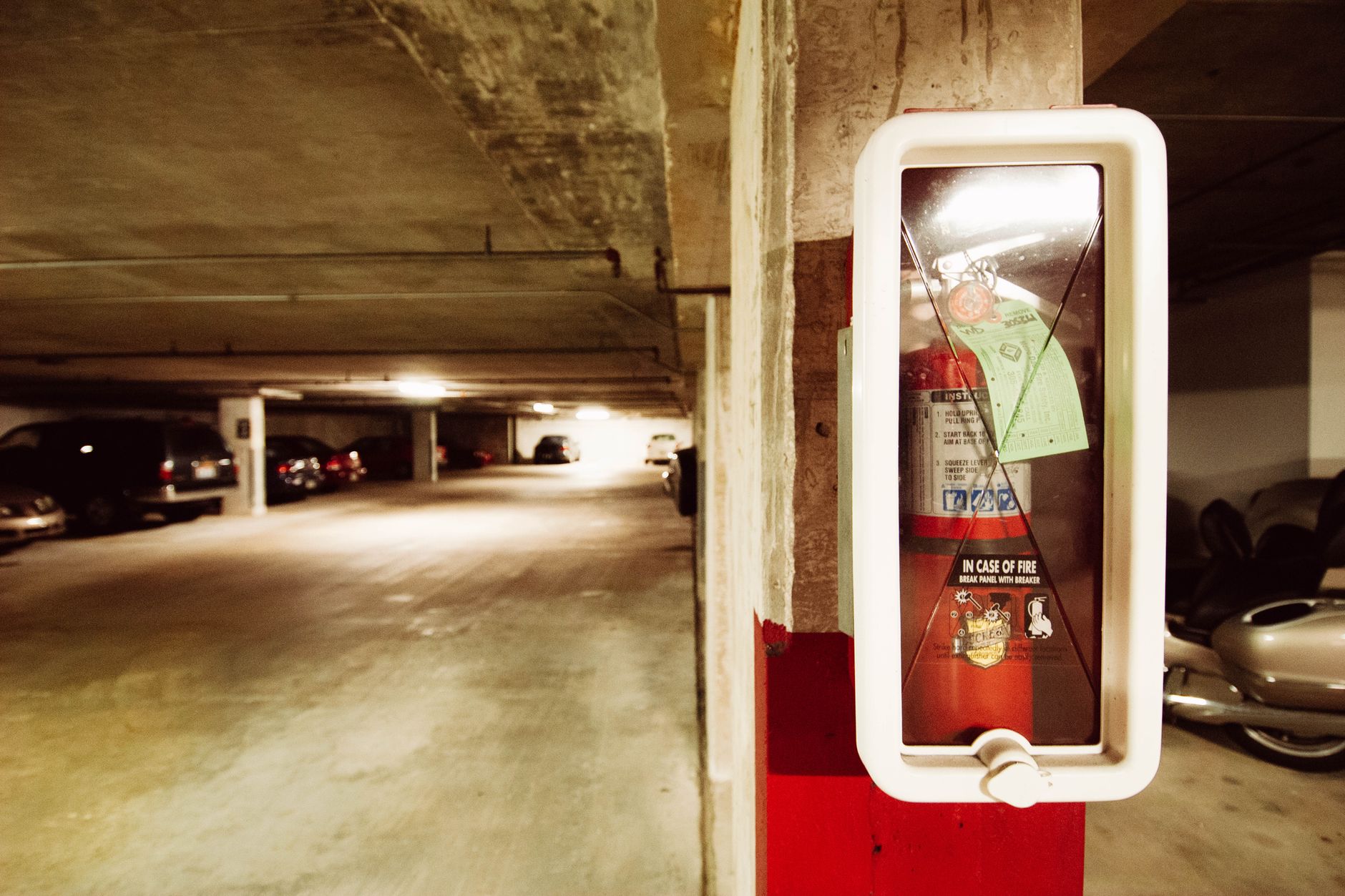 Long interior aisle inside a multilevel parking garage, illustrating the repetitive patrol environment where persistent coverage matters more than occasional rounds.