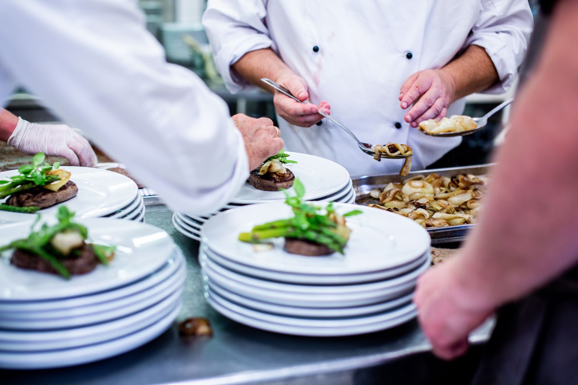 Kitchen staff plate finished dishes at a busy commercial restaurant pass.