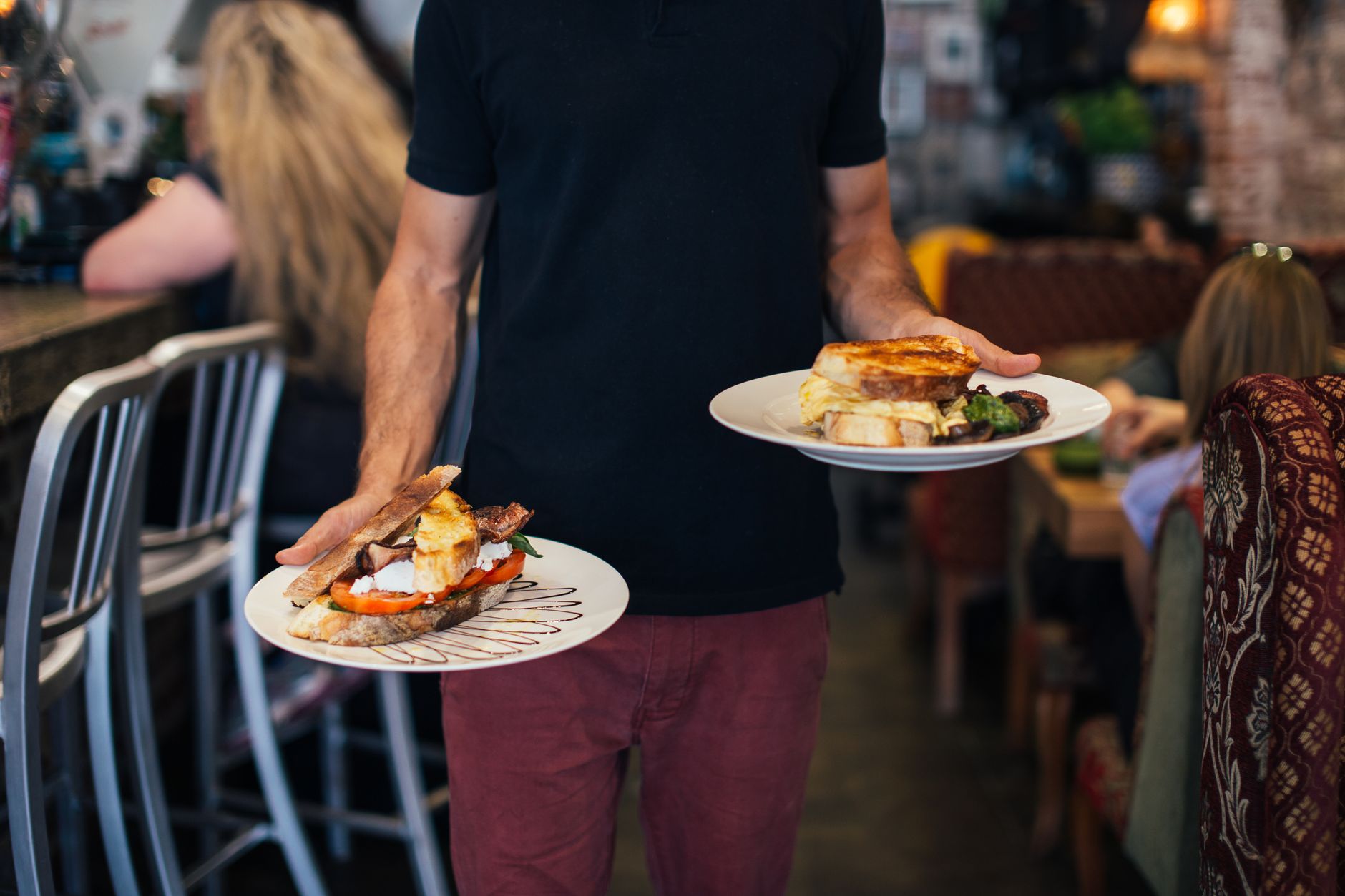 A restaurant server personally presents a dish and speaks with guests at their table.