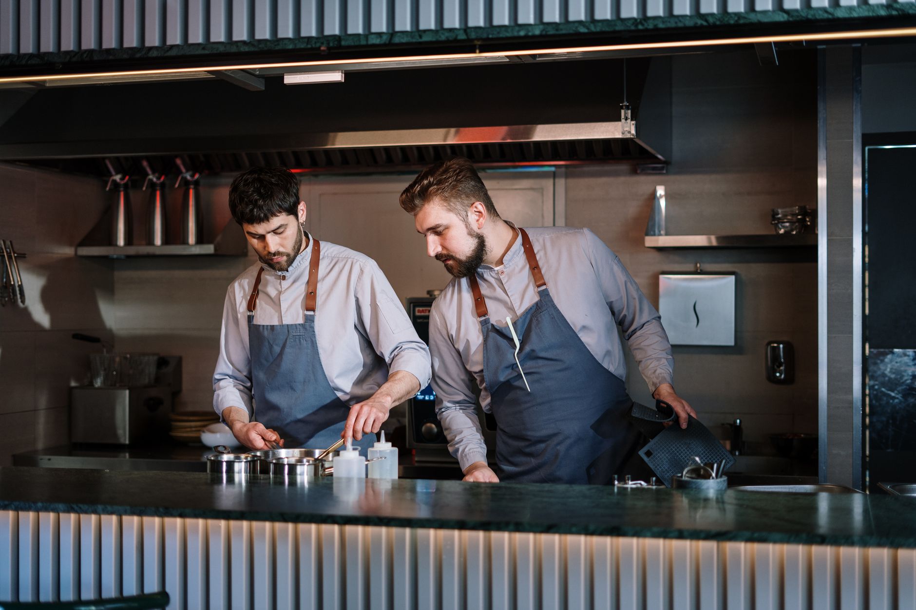 A restaurant kitchen pass area where staff coordinate handoffs and prep for the next table turn.
