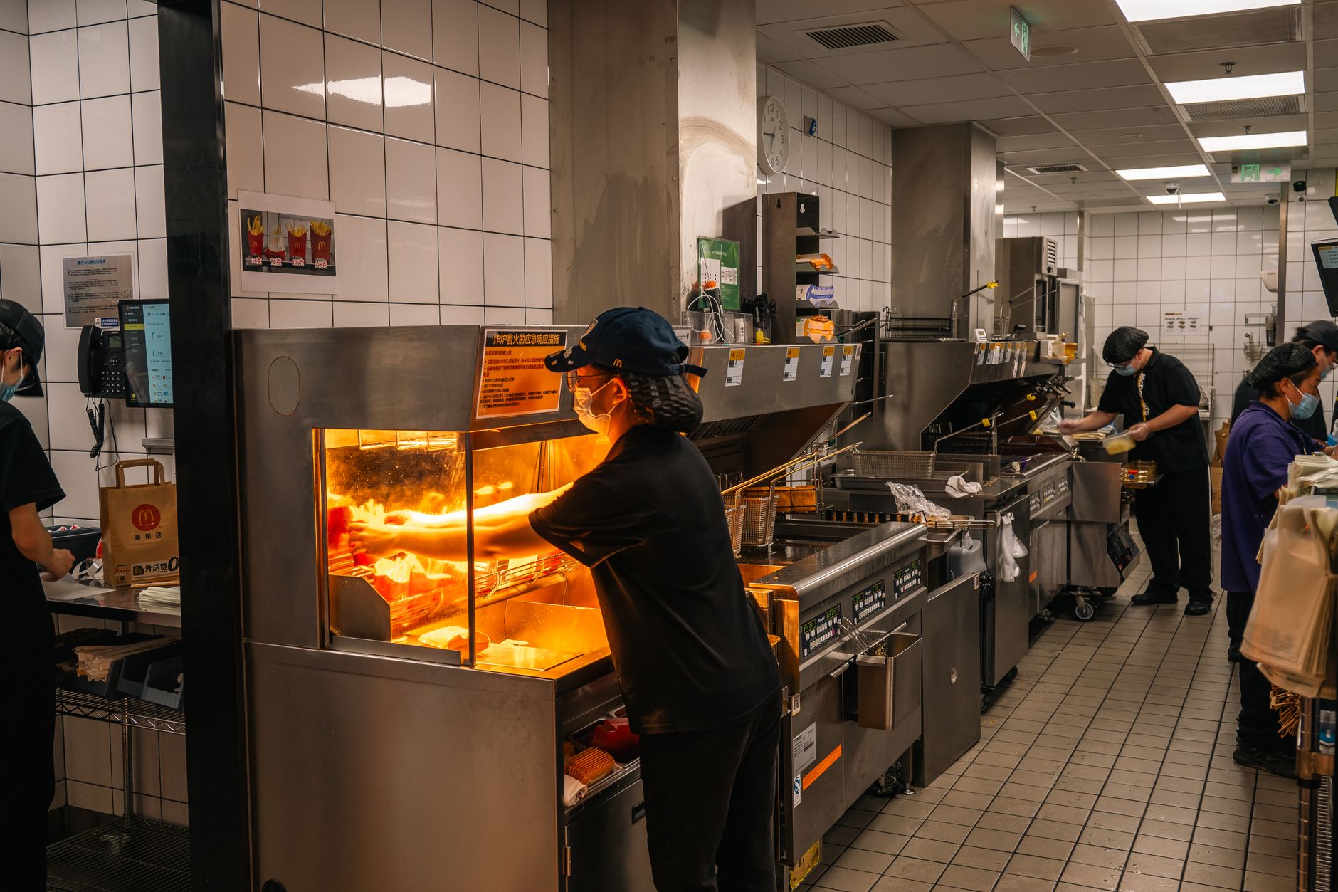 Restaurant employees work together during a busy shift in a quick-service kitchen.