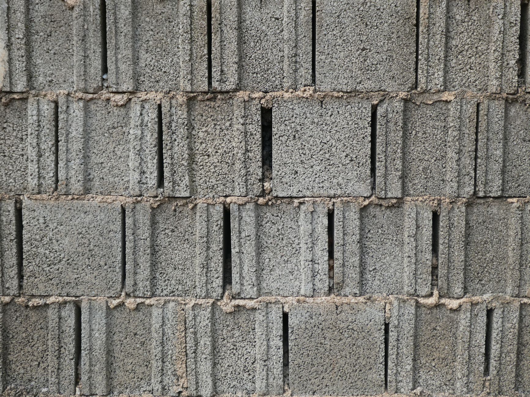 Concrete masonry blocks stacked beside a newly built wall on a housing site.