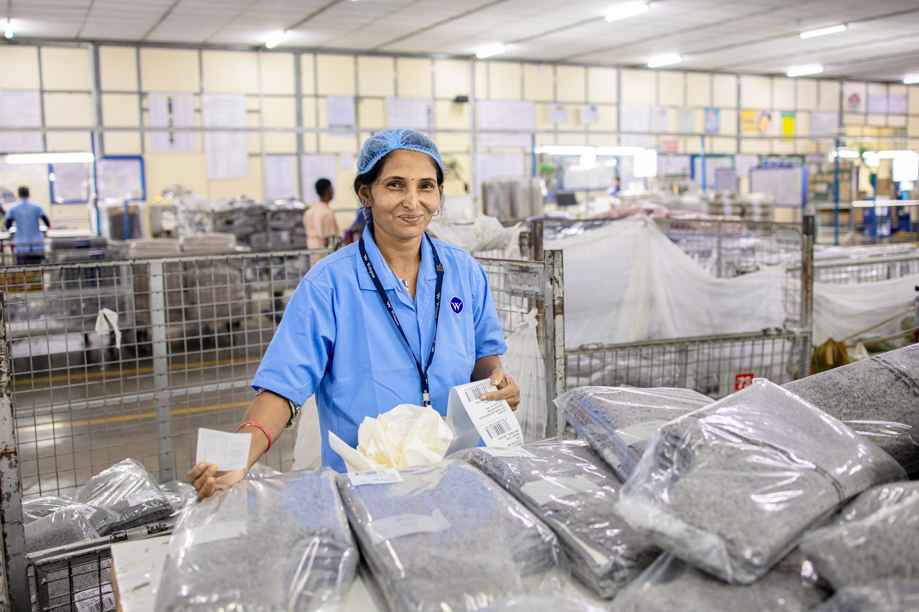 A production worker prepares cartons and labels at a compact manufacturing packaging station.