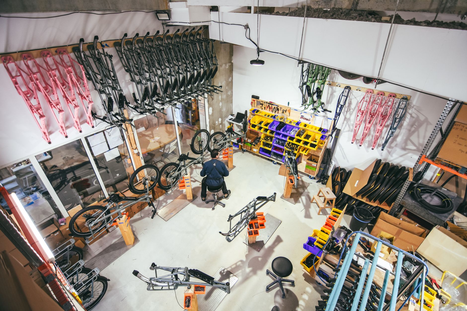 A fitter assembles structural frame profiles at a workbench in a compact production workshop.