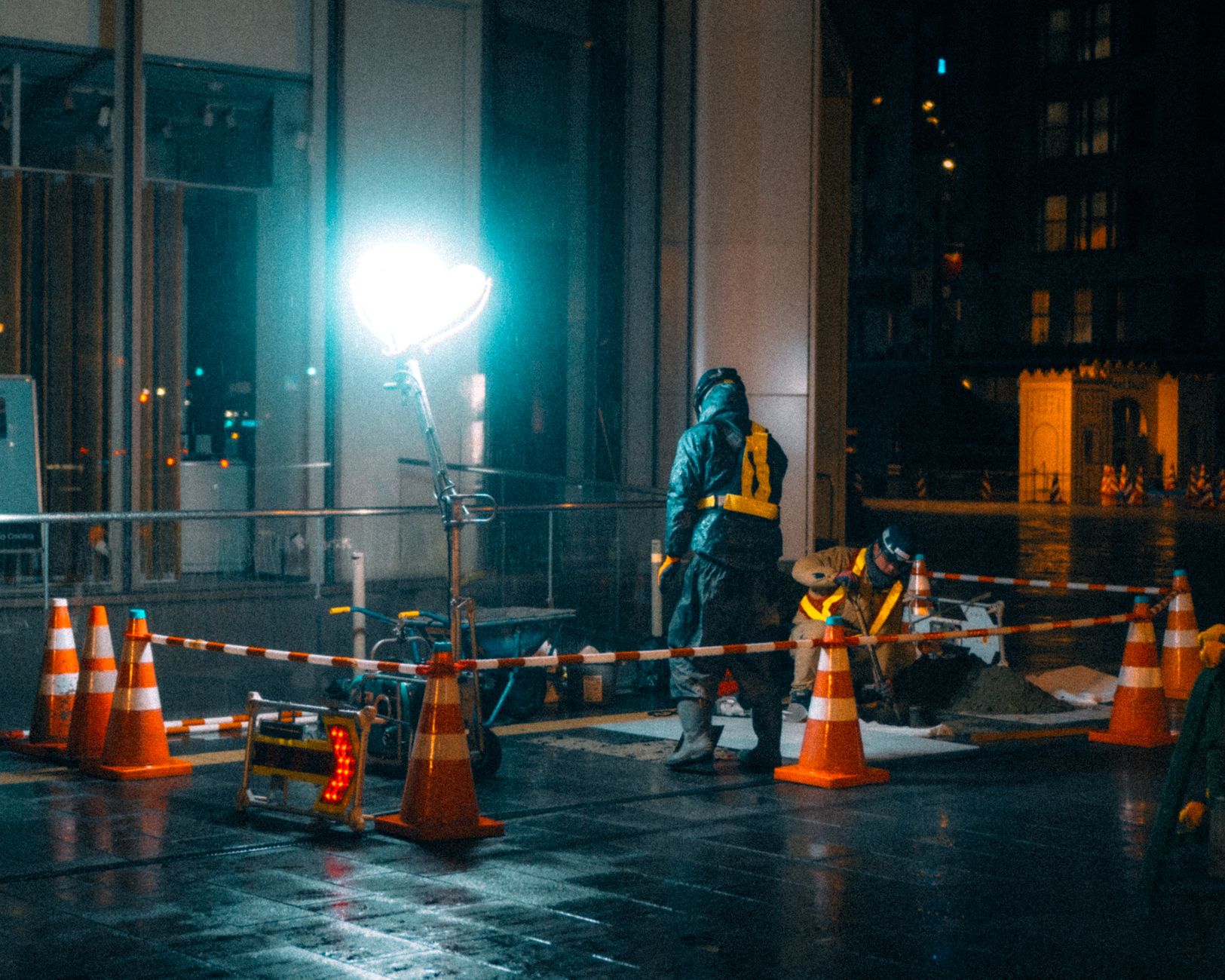 Night lane-closure setup on a freeway work zone, with traffic cones guiding vehicles past construction.