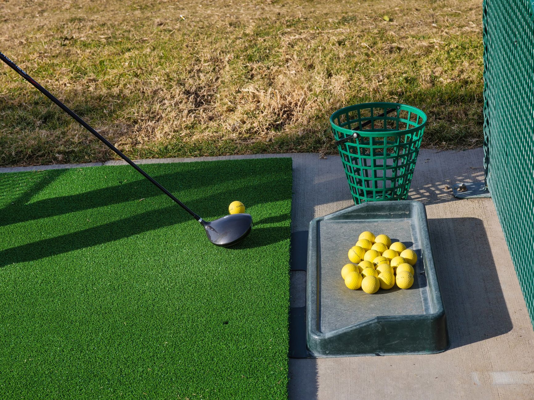 A multi-level golf practice range with rows of hitting bays overlooking the field.