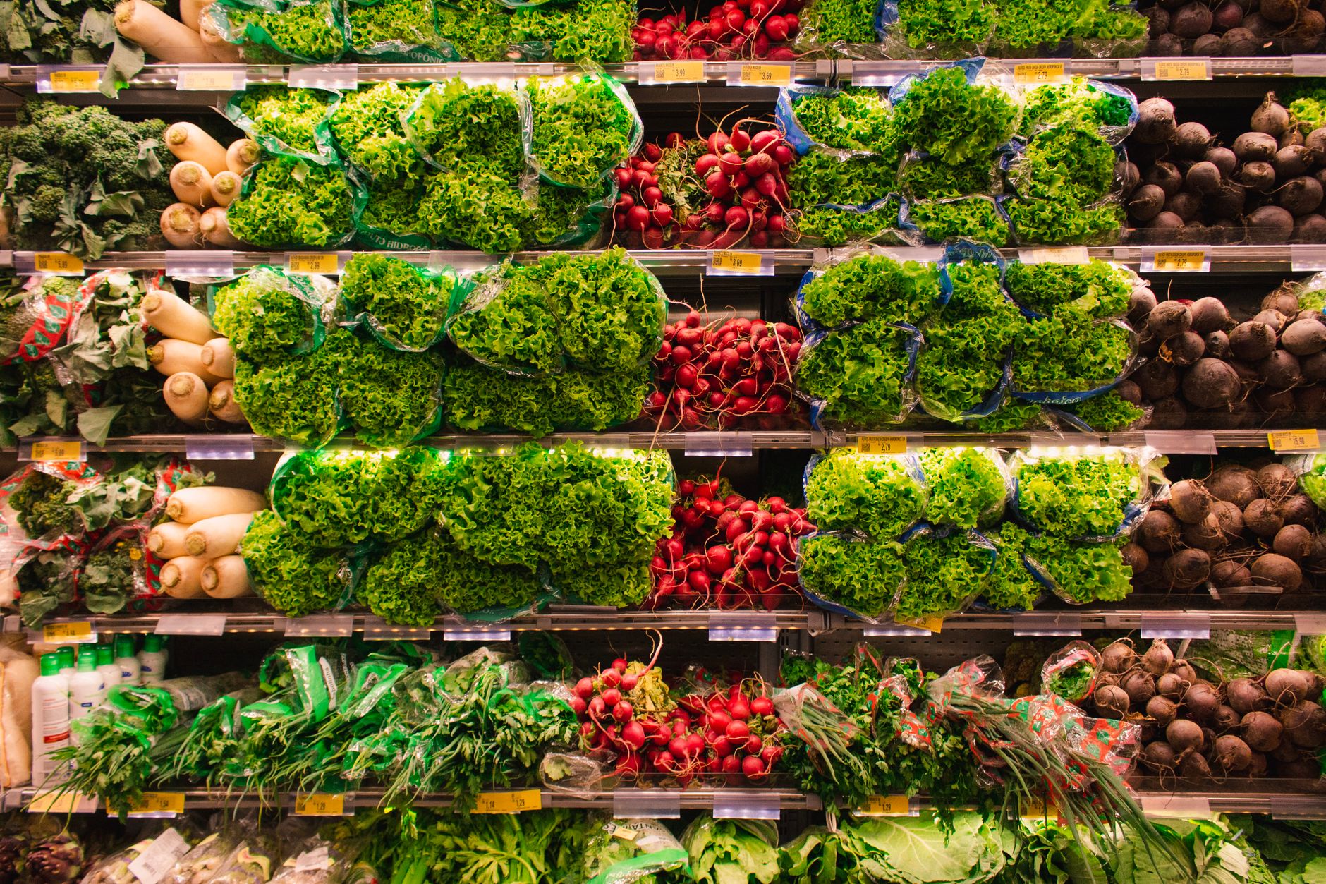 Busy supermarket aisle where manual floor cleaning competes with customer service tasks.