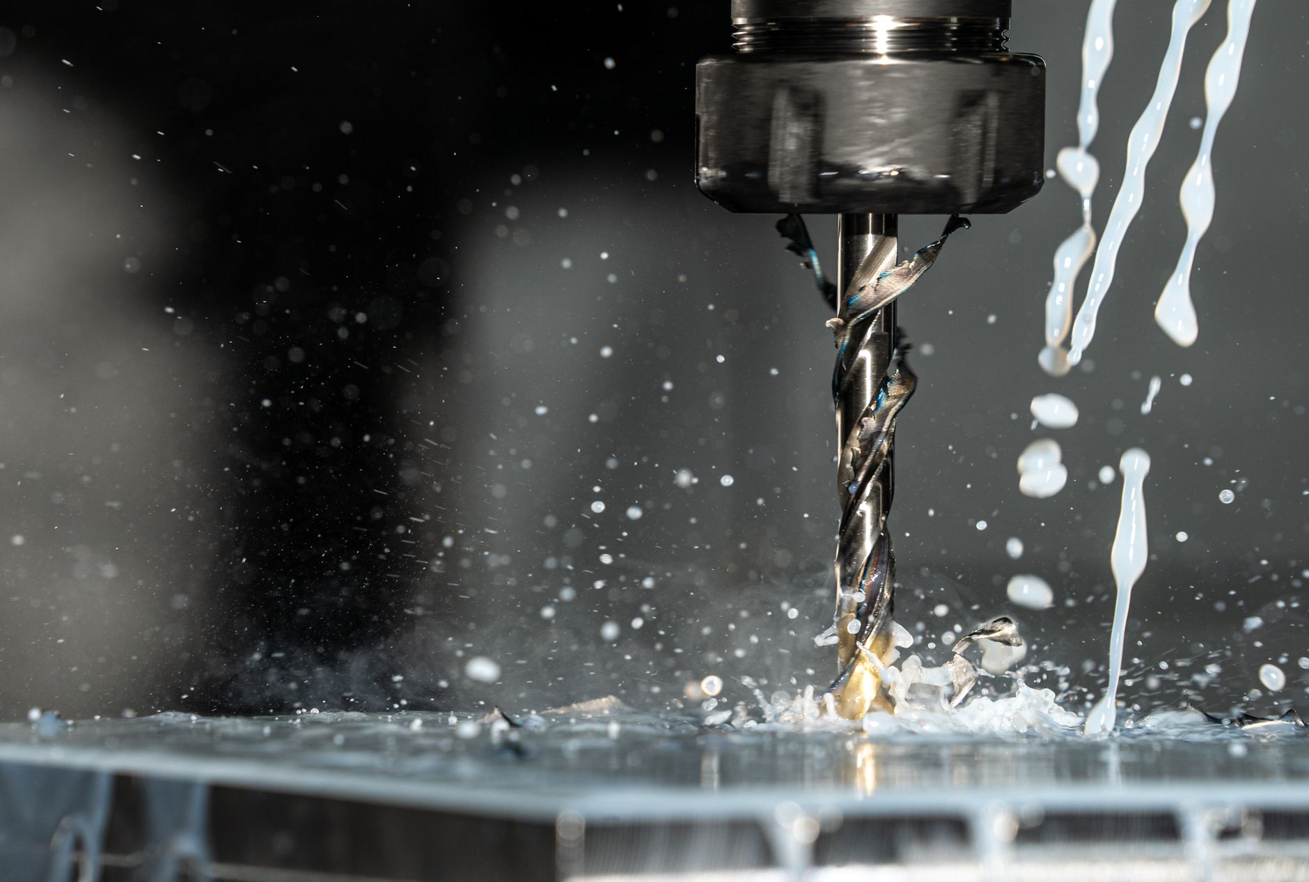 A metal drilling station working on aluminum parts in a machine shop.