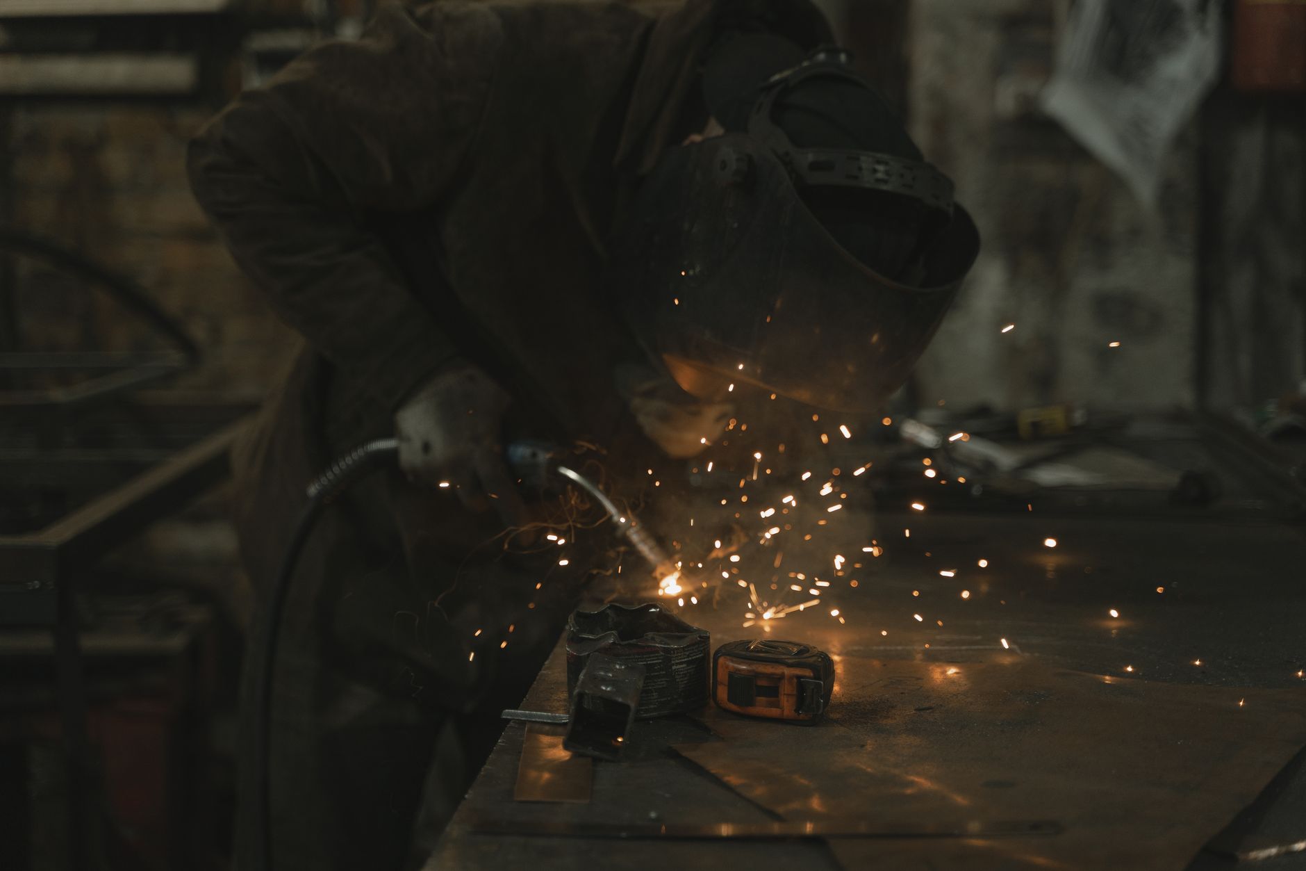 A metalworker guides a plasma torch through thick steel plate as sparks scatter across the shop floor.