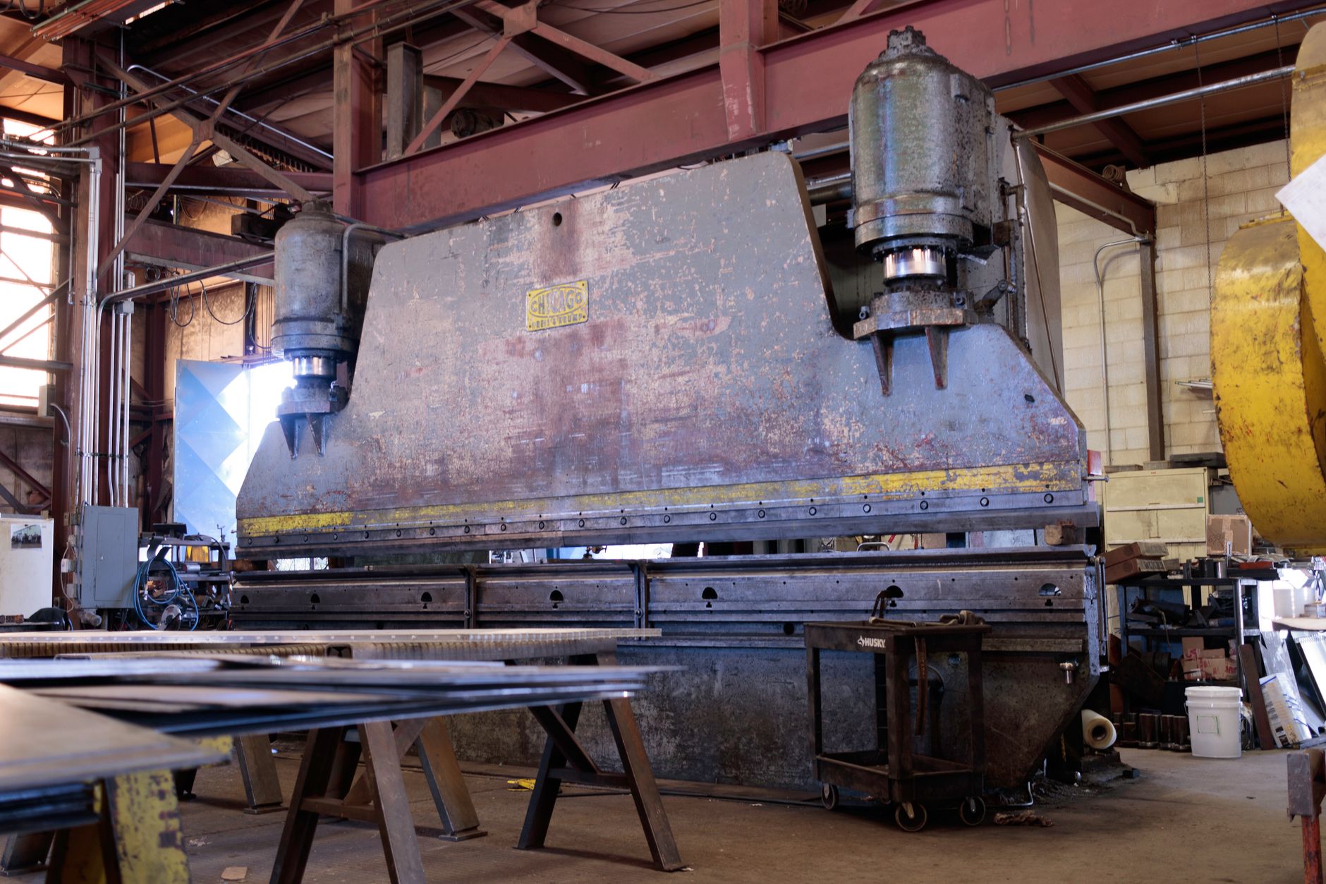 A welder works among oversized steel assemblies in a heavy fabrication shop.