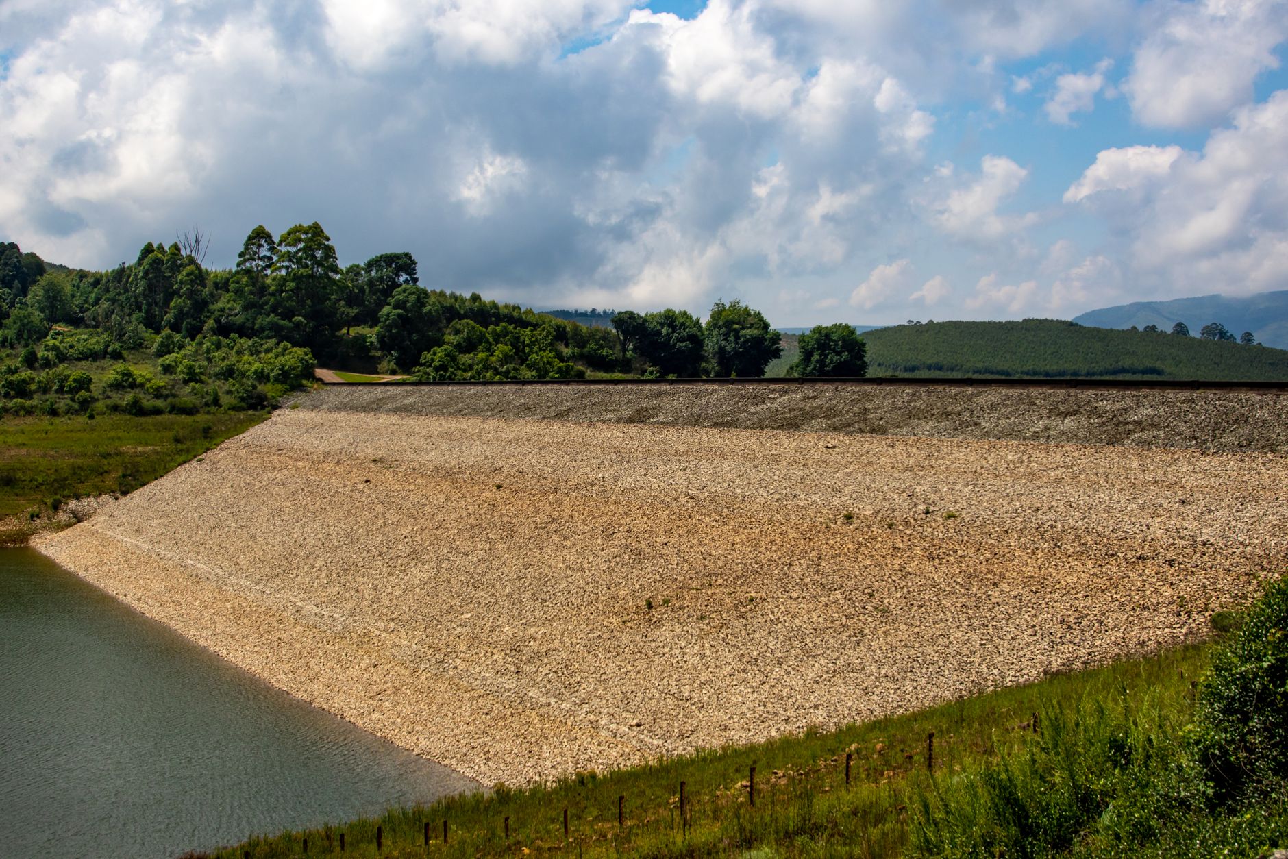 A steep gravel embankment beside a highway where crews staged access to a buried culvert.