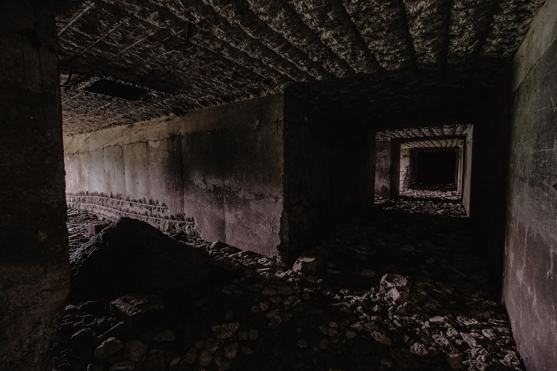Broken concrete and demolition debris fill a confined basement work area.