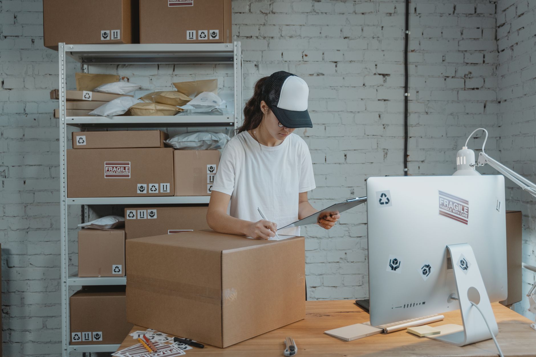 Associates prepare e-commerce cartons at a packing bench as small-item volume grows inside a large DC.