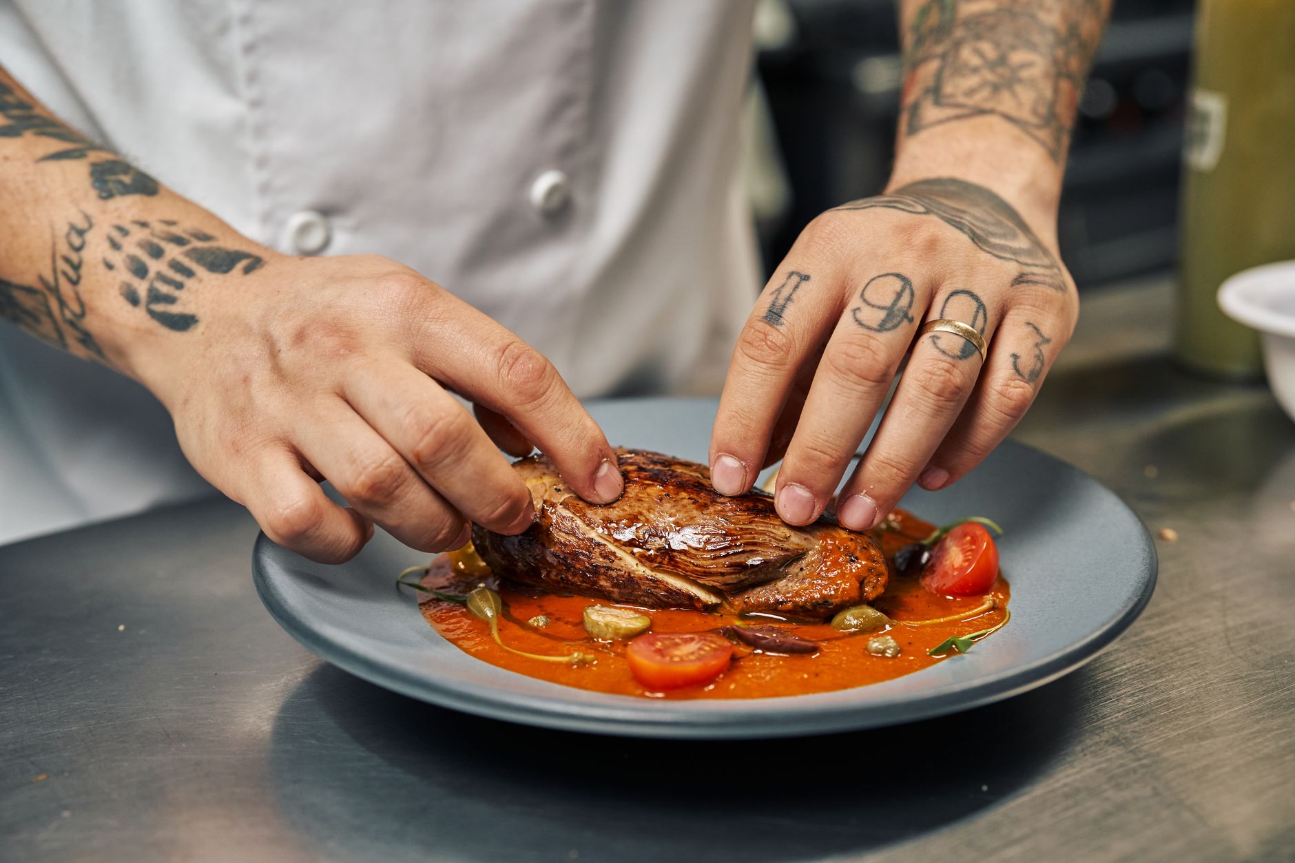 Kitchen staff preparing plated dishes at a pass while dining room demand stays high.